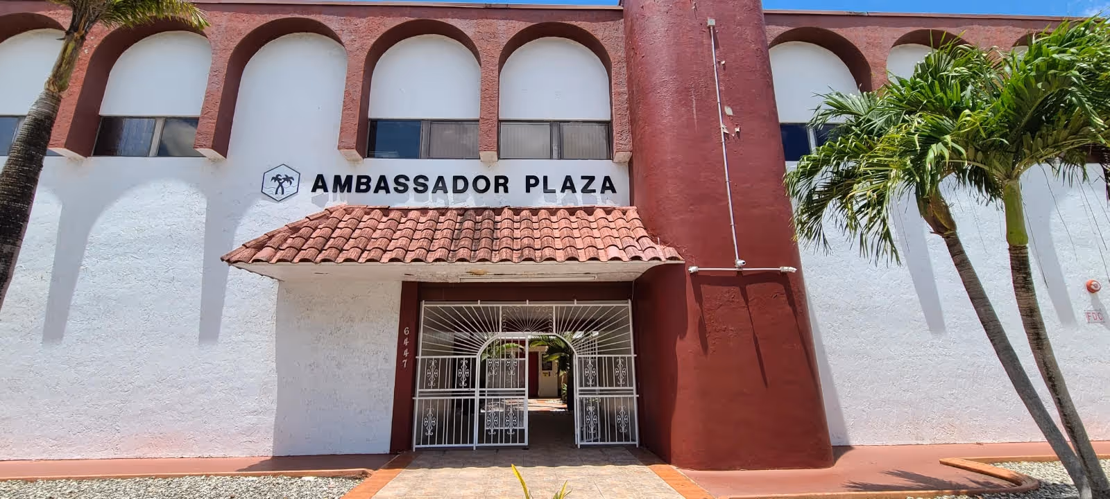 Front exterior of a building with a gated entrance labeled Ambassador Plaza.