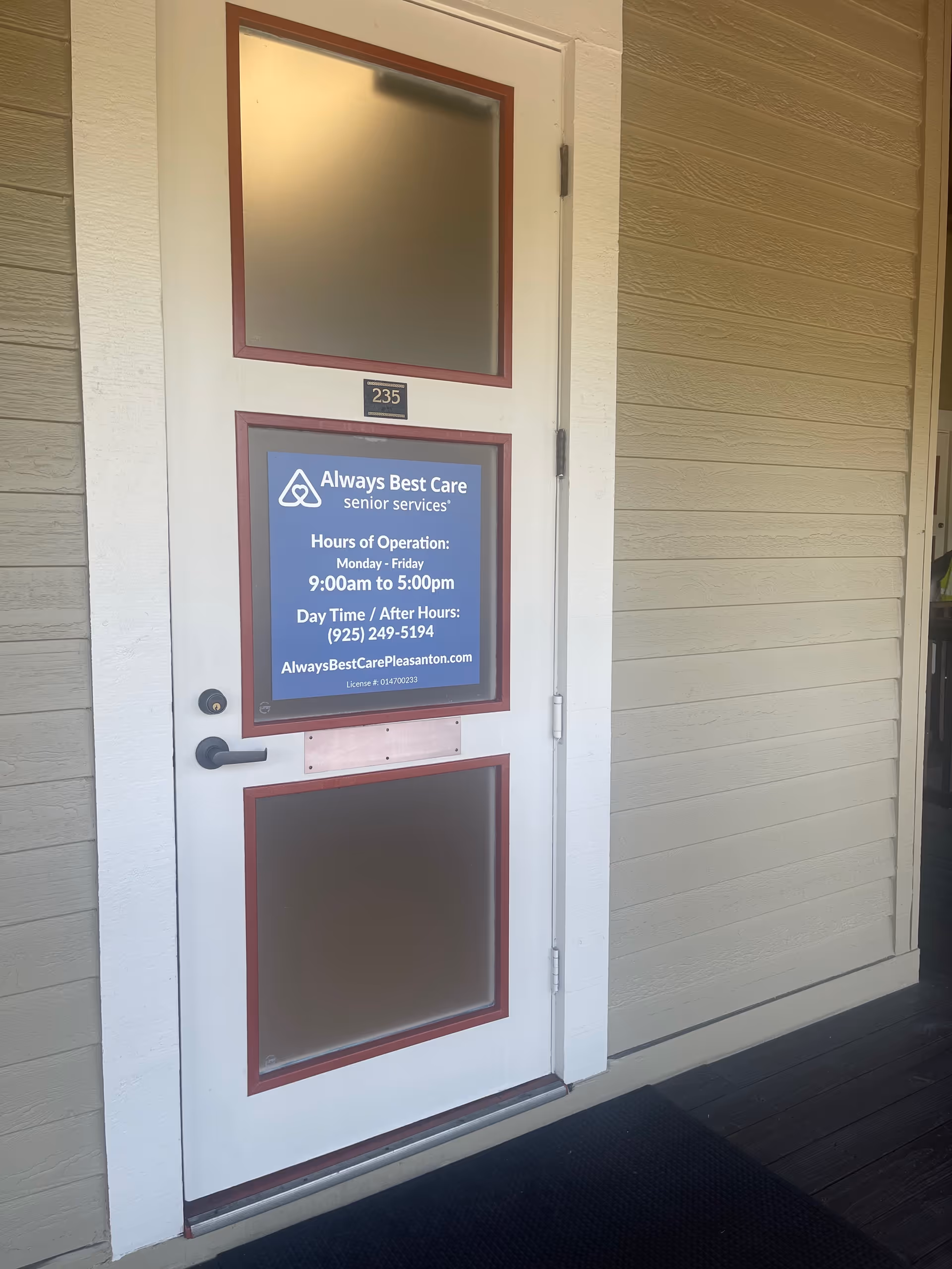 White front door with blue Always Best Care sign on beige building exterior.