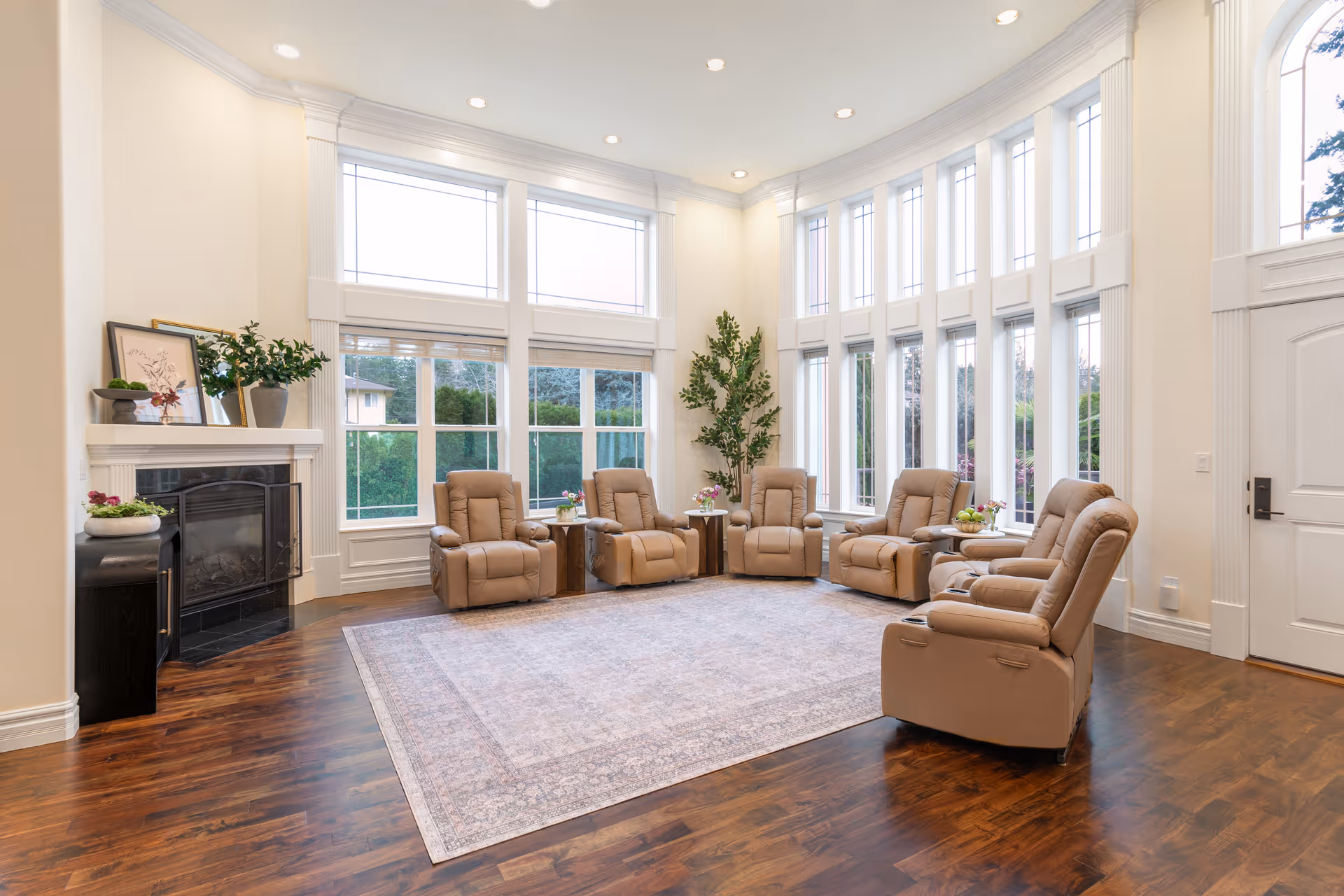 Bright senior living lounge with beige recliners, large windows, and a fireplace.