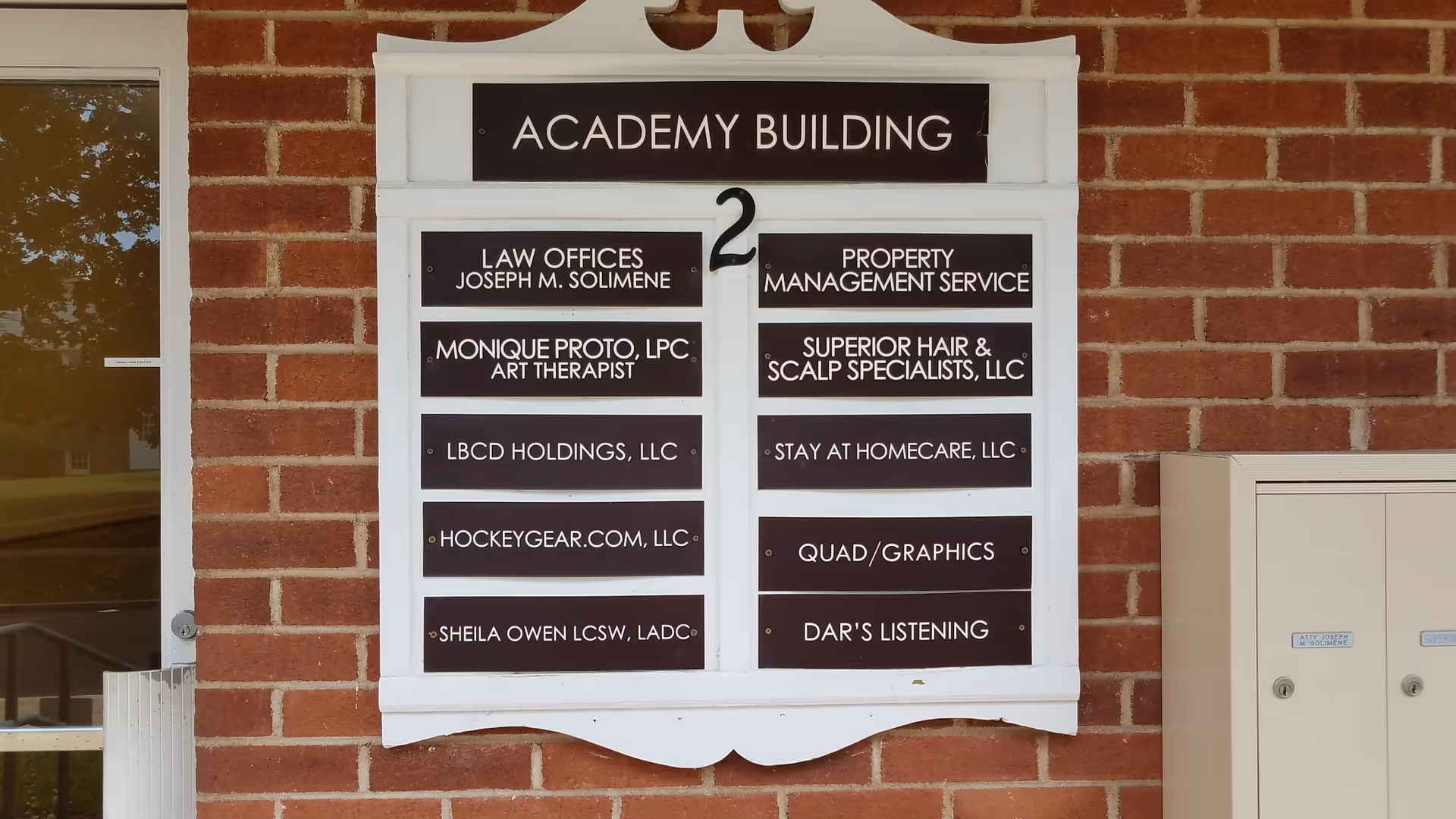 Brick building facade with a white directory sign listing tenants including Stay At Home Care, LLC.