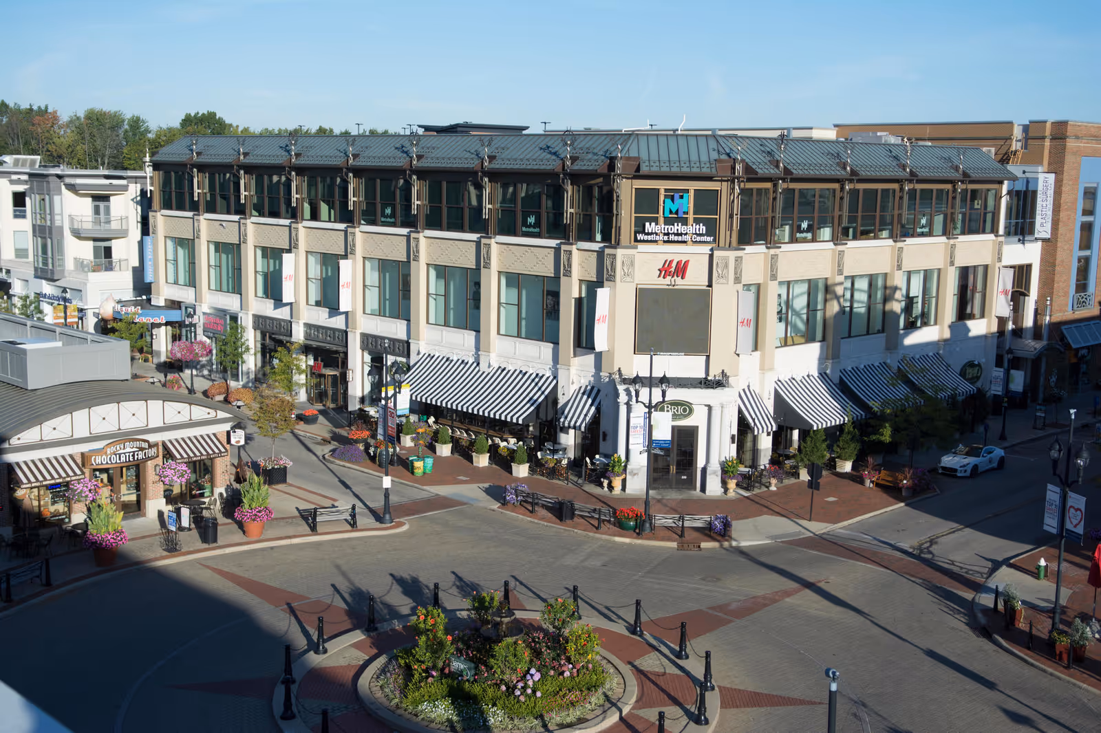 Exterior view of a multi-story shopping plaza with MetroHealth sign and striped storefront awnings.