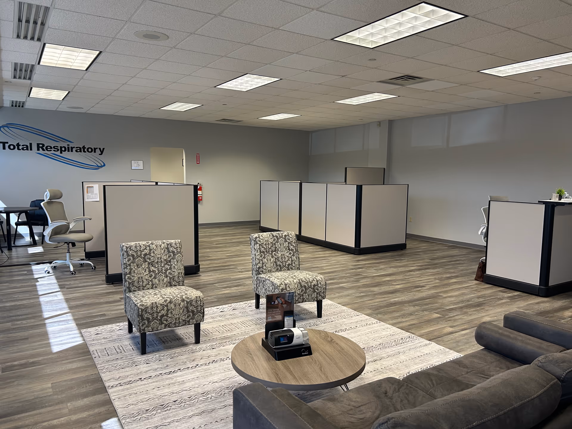 Reception area with Total Respiratory logo, cubicles, and lounge seating in a modern interior.
