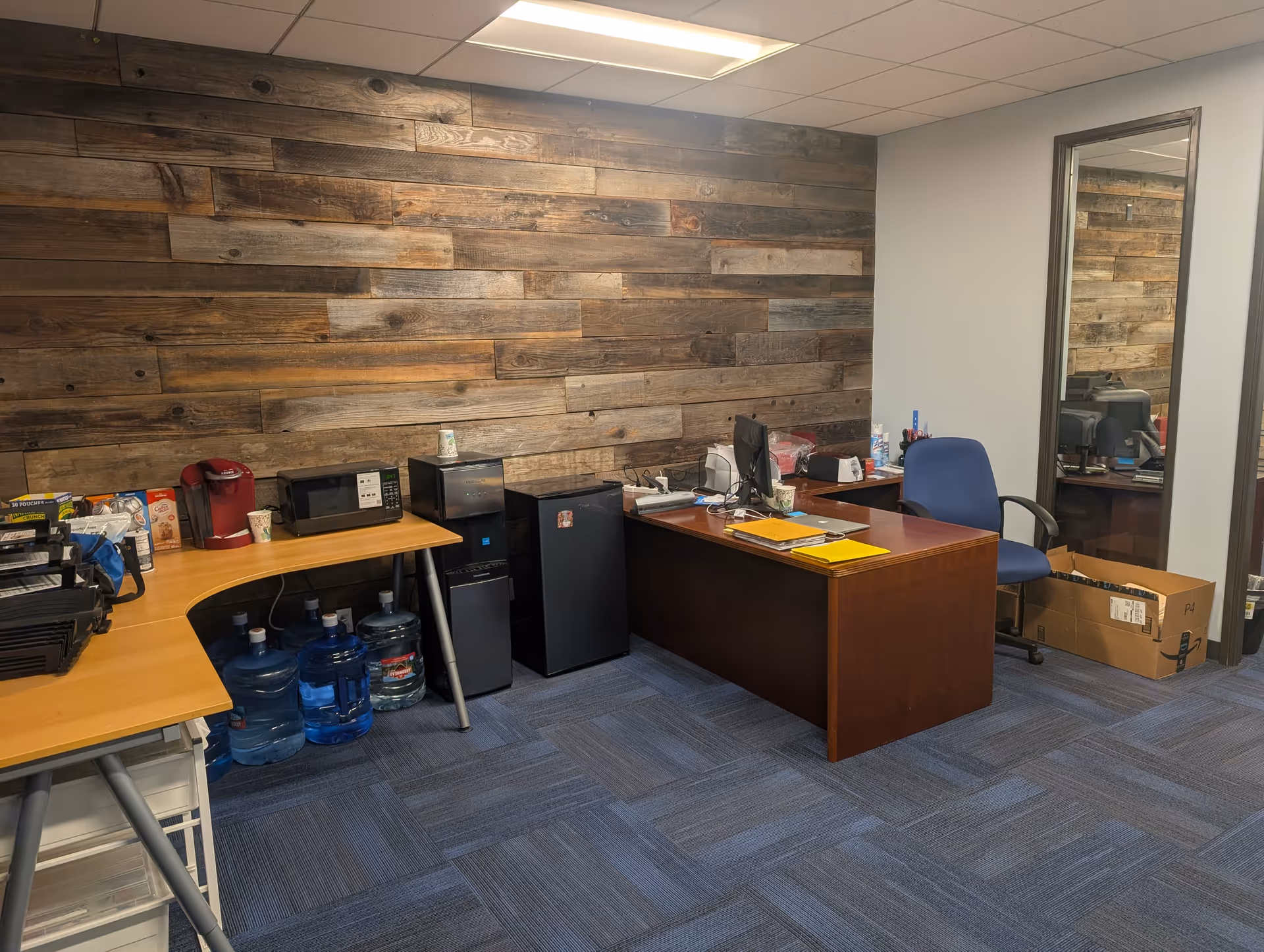 Office workspace with desk, chairs, water cooler, and wood-paneled accent wall