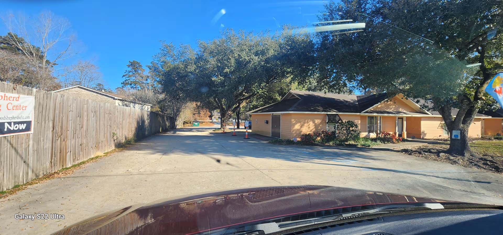 Exterior view of a single-story senior living facility with a driveway and trees.