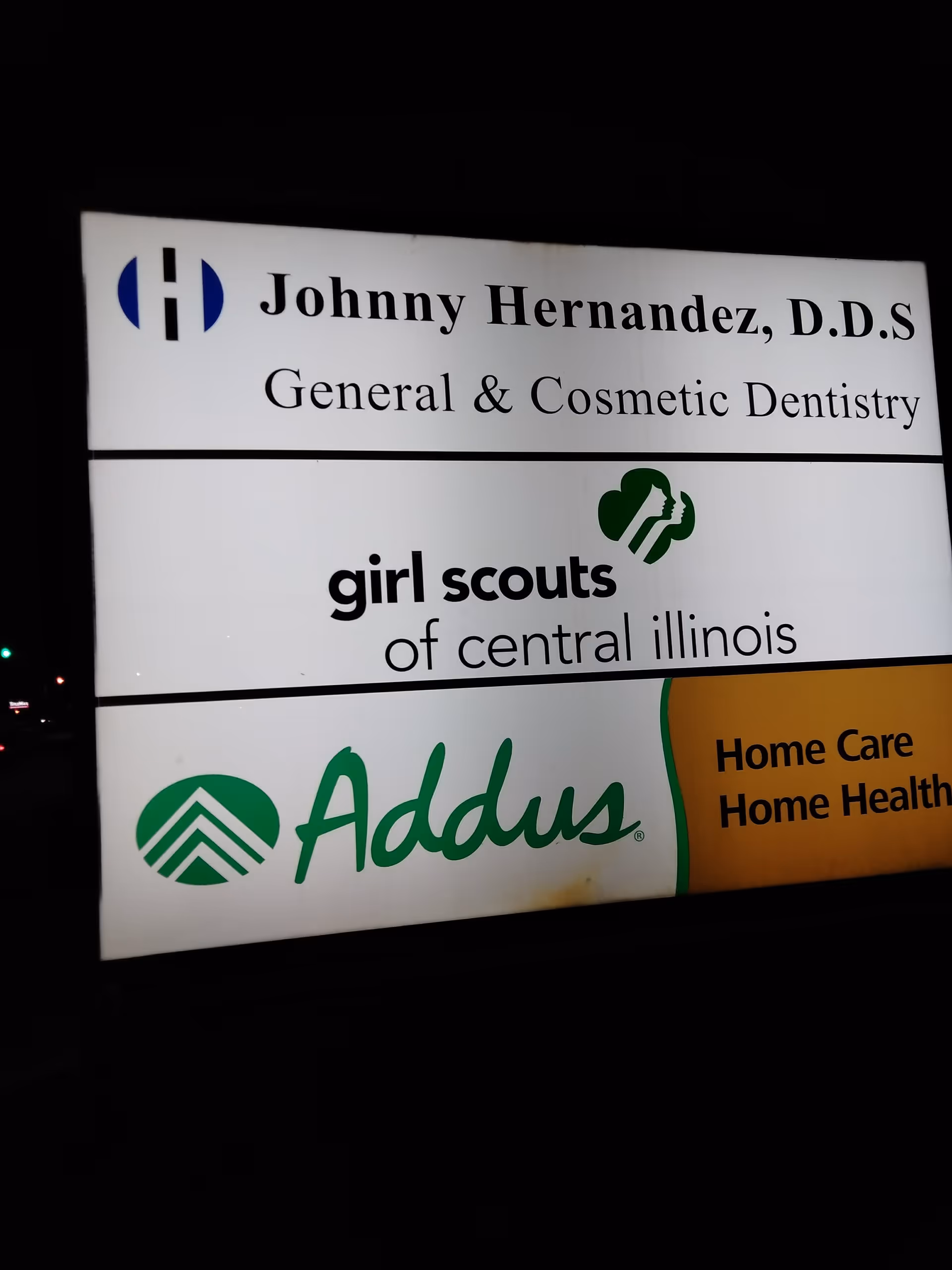 Night-time exterior signboard featuring Addus Home Care and other tenants.