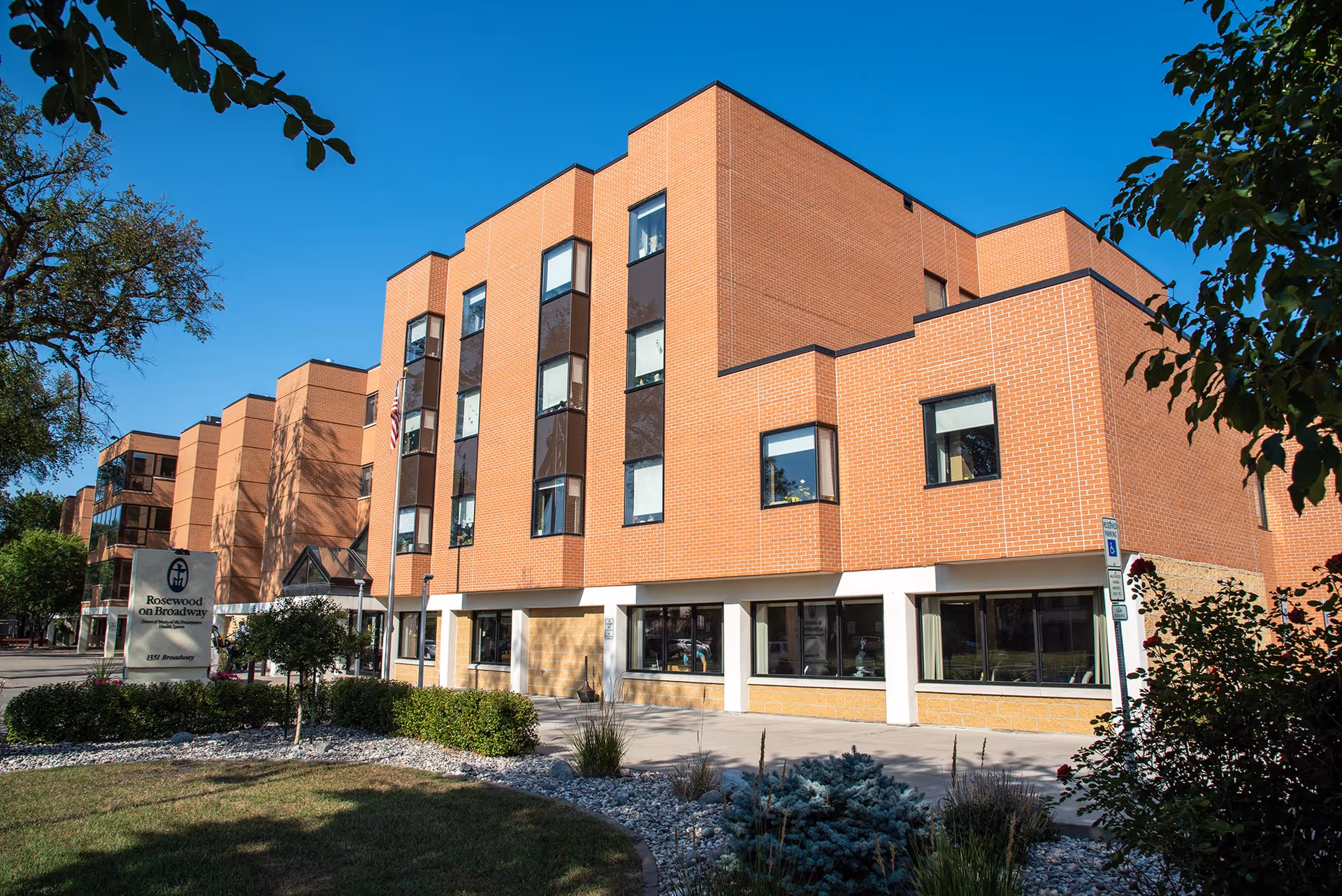 Brick multi-story Rosewood on Broadway senior living building with front entrance and landscaping.