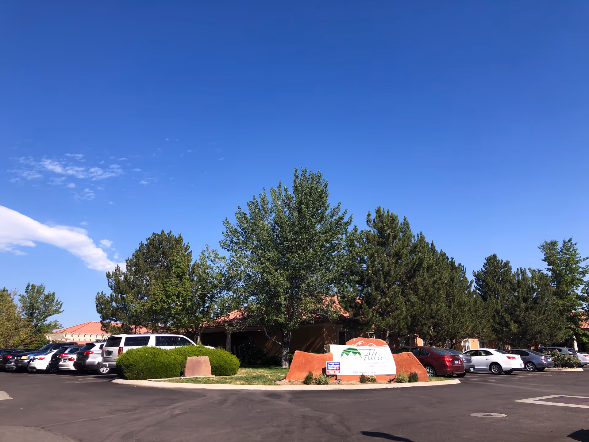 Exterior view of Alta Skilled Nursing and Rehabilitation Center with parked cars and trees.