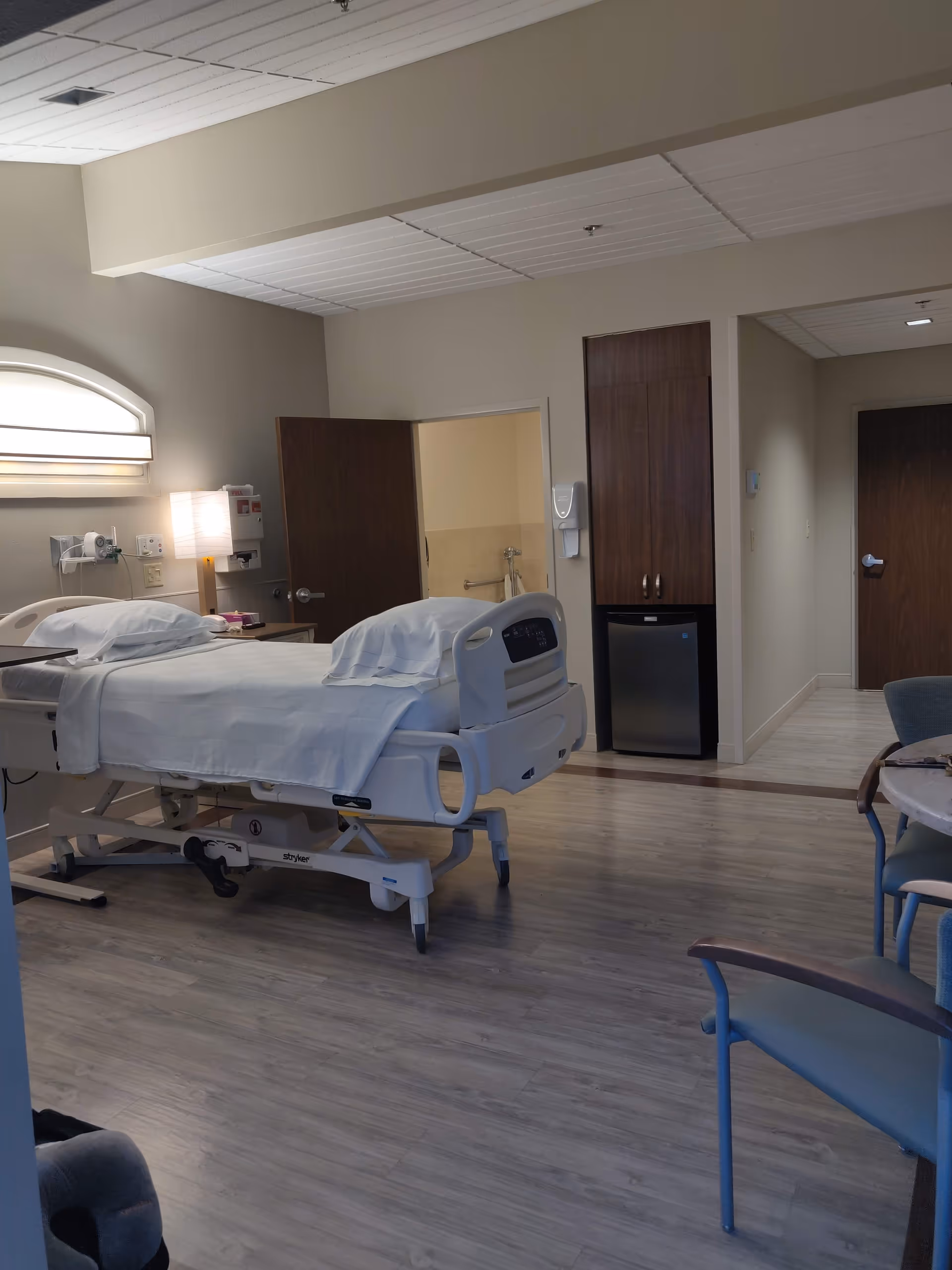 Hospice patient room with an adjustable bed, medical equipment, and seating.