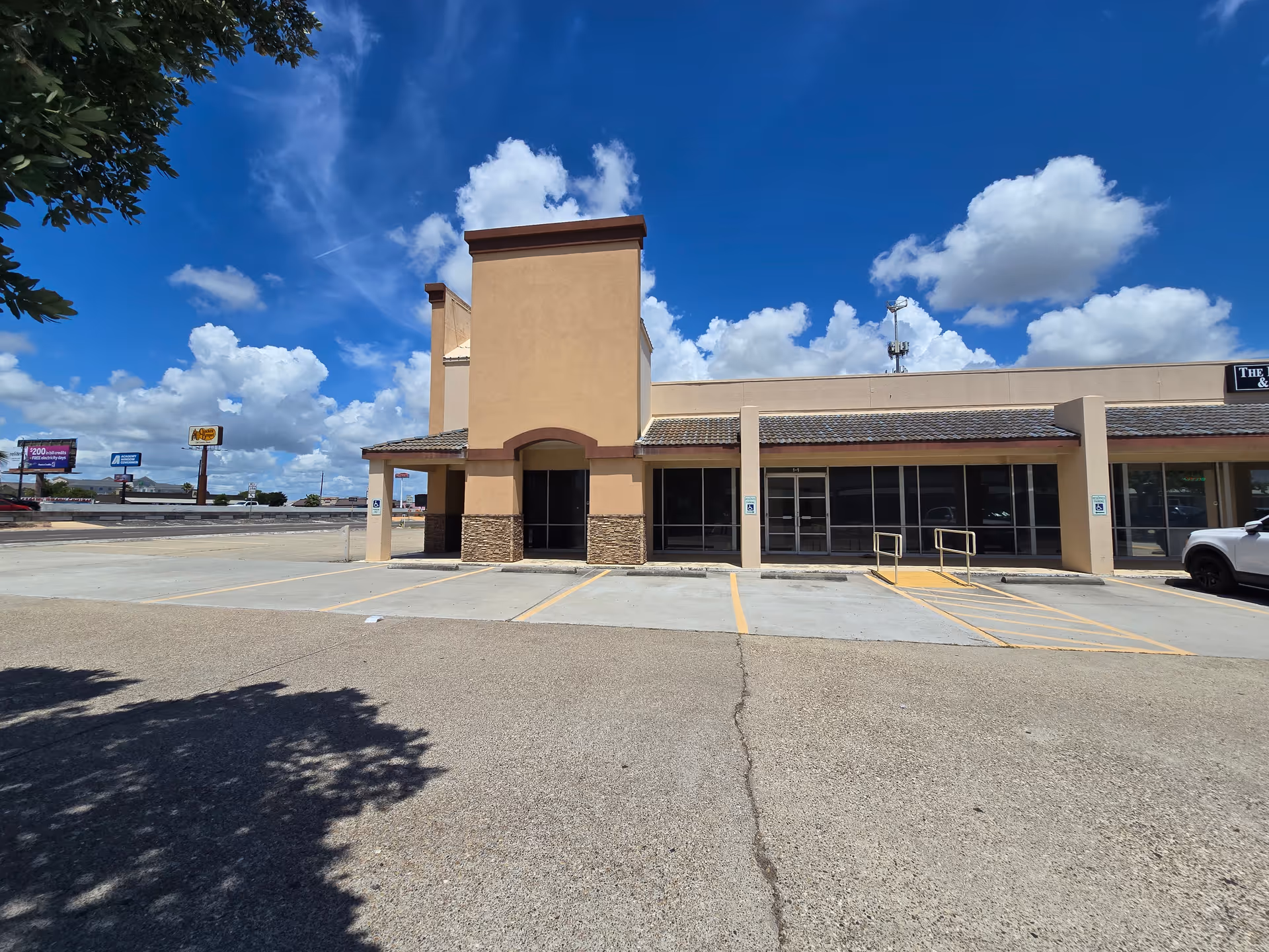 Exterior view of a single-story beige building with a parking lot and blue sky.