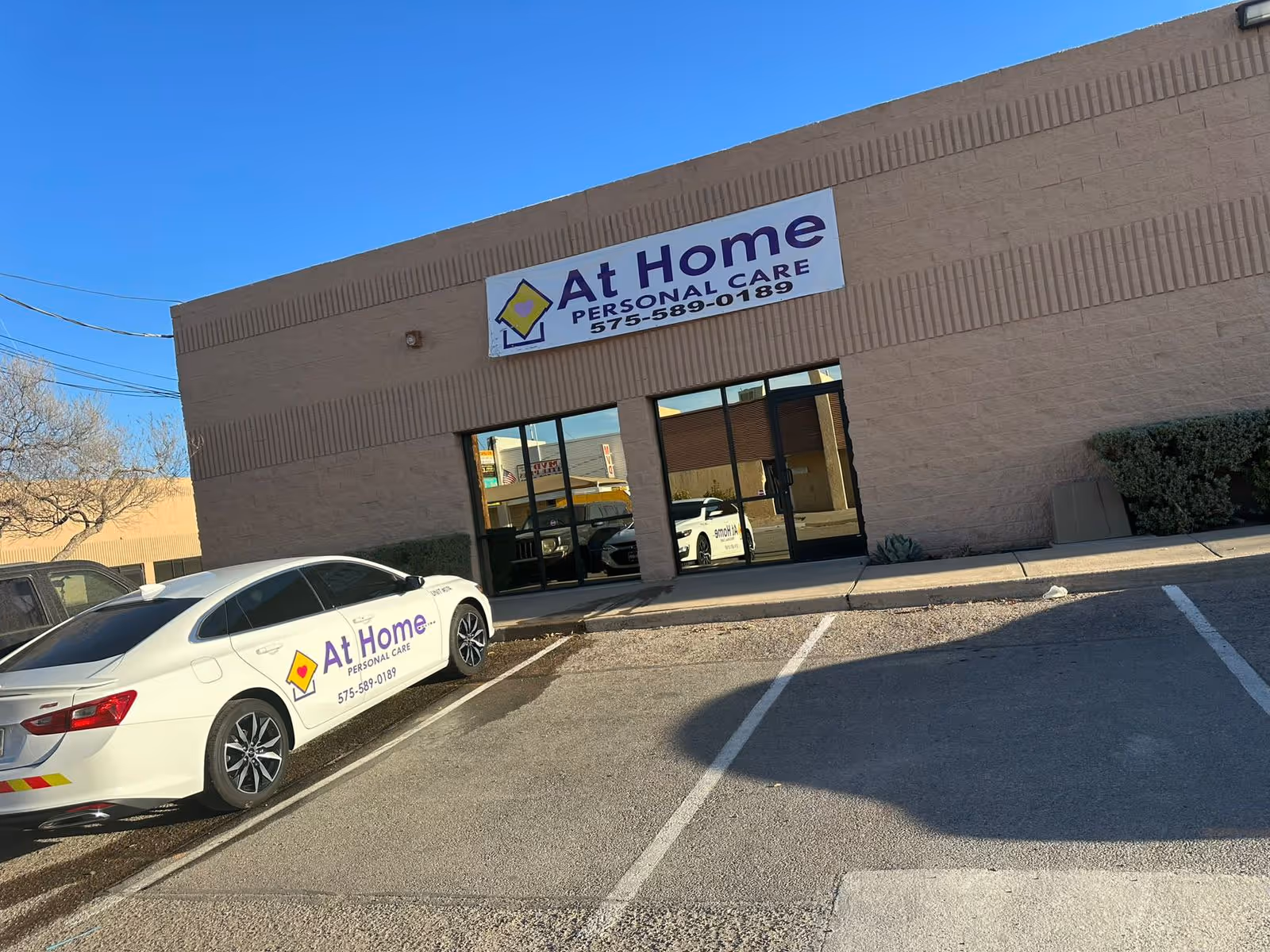Front view of At Home Personal Care building with parked cars