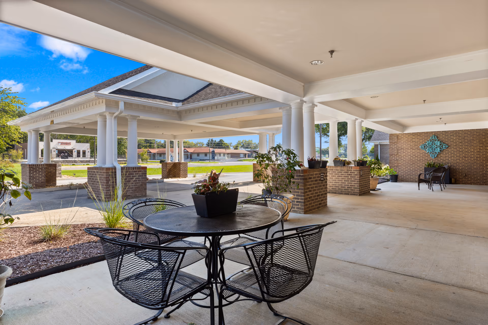 Covered outdoor patio at Shannondale Assisted Living Center with seating and planters.