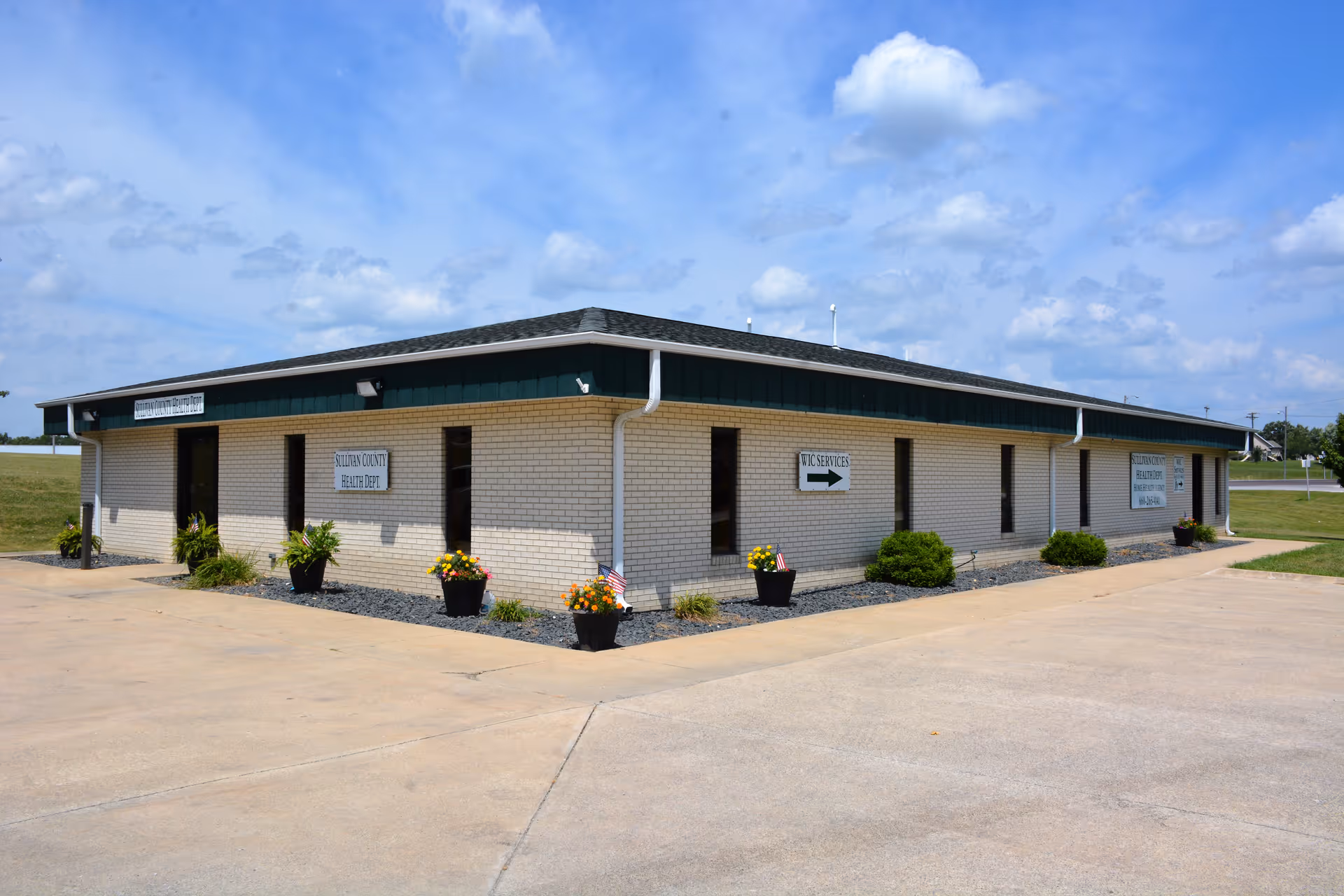 Sullivan County Health Department building exterior with signs, green trim, and potted plants.