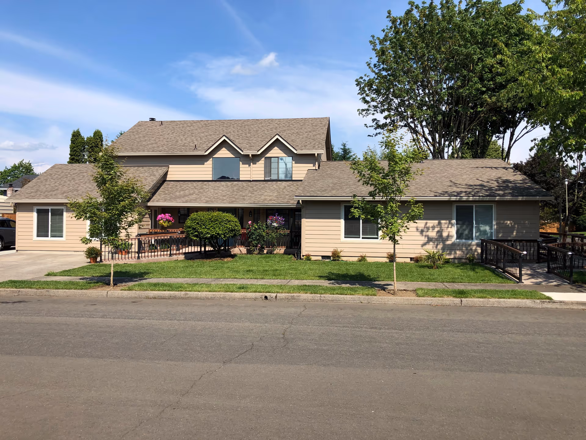 Exterior view of a beige senior care facility with a manicured lawn and trees.