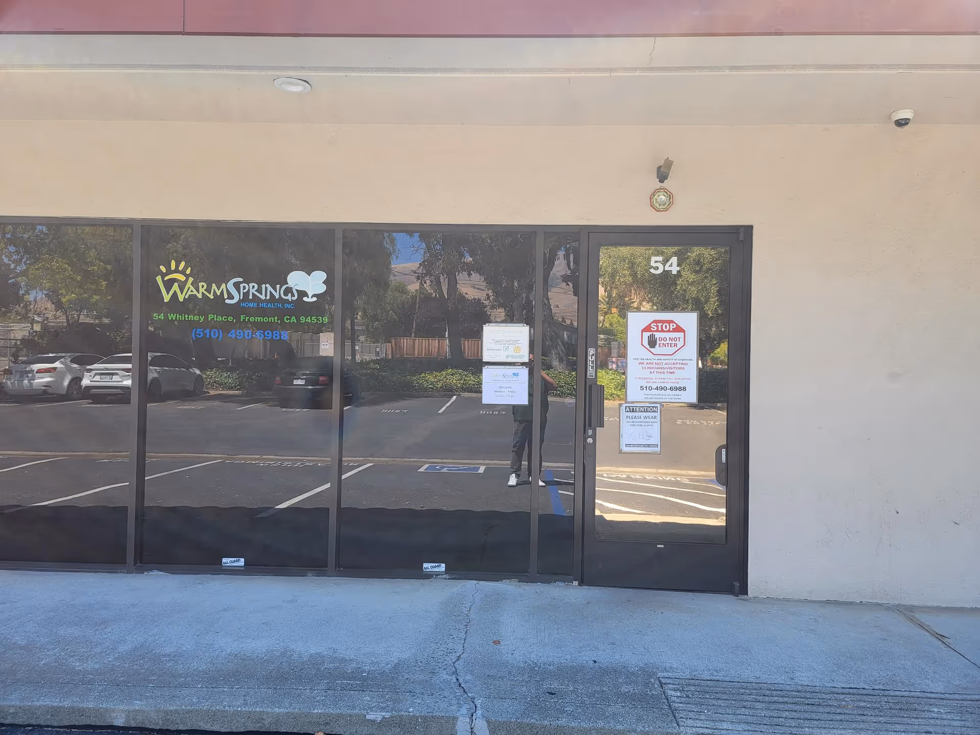 Exterior storefront of Warm Springs Home Health with glass doors and a parking lot.
