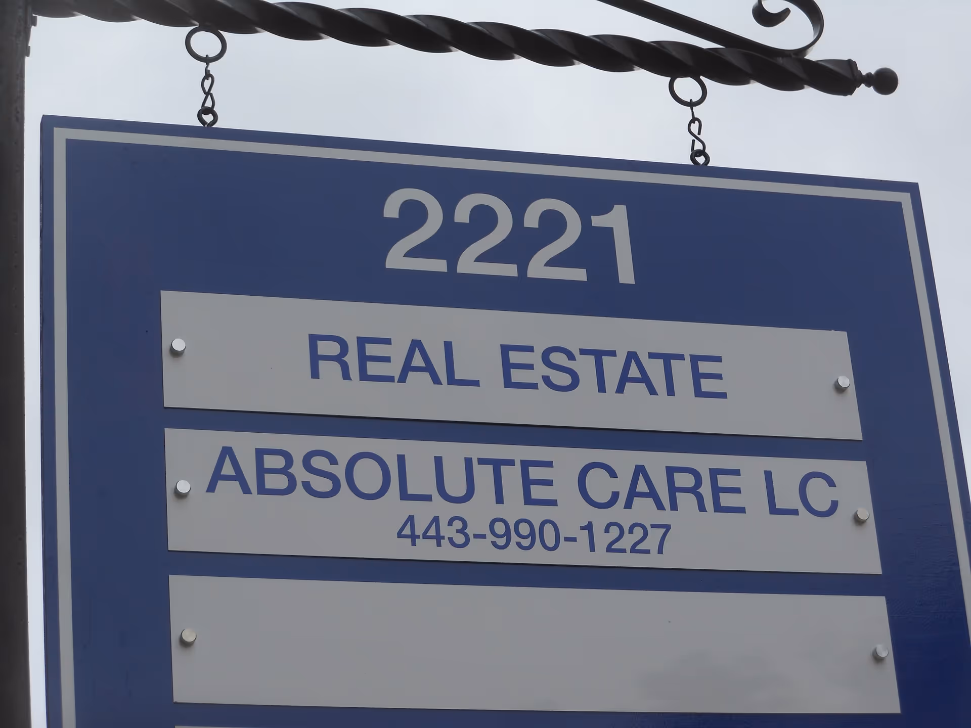 Blue real estate sign on building frontage for Absolute Care LC