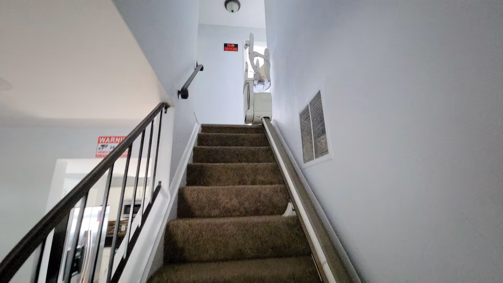 Interior stairwell with carpeted stairs and metal handrails at a senior living facility.