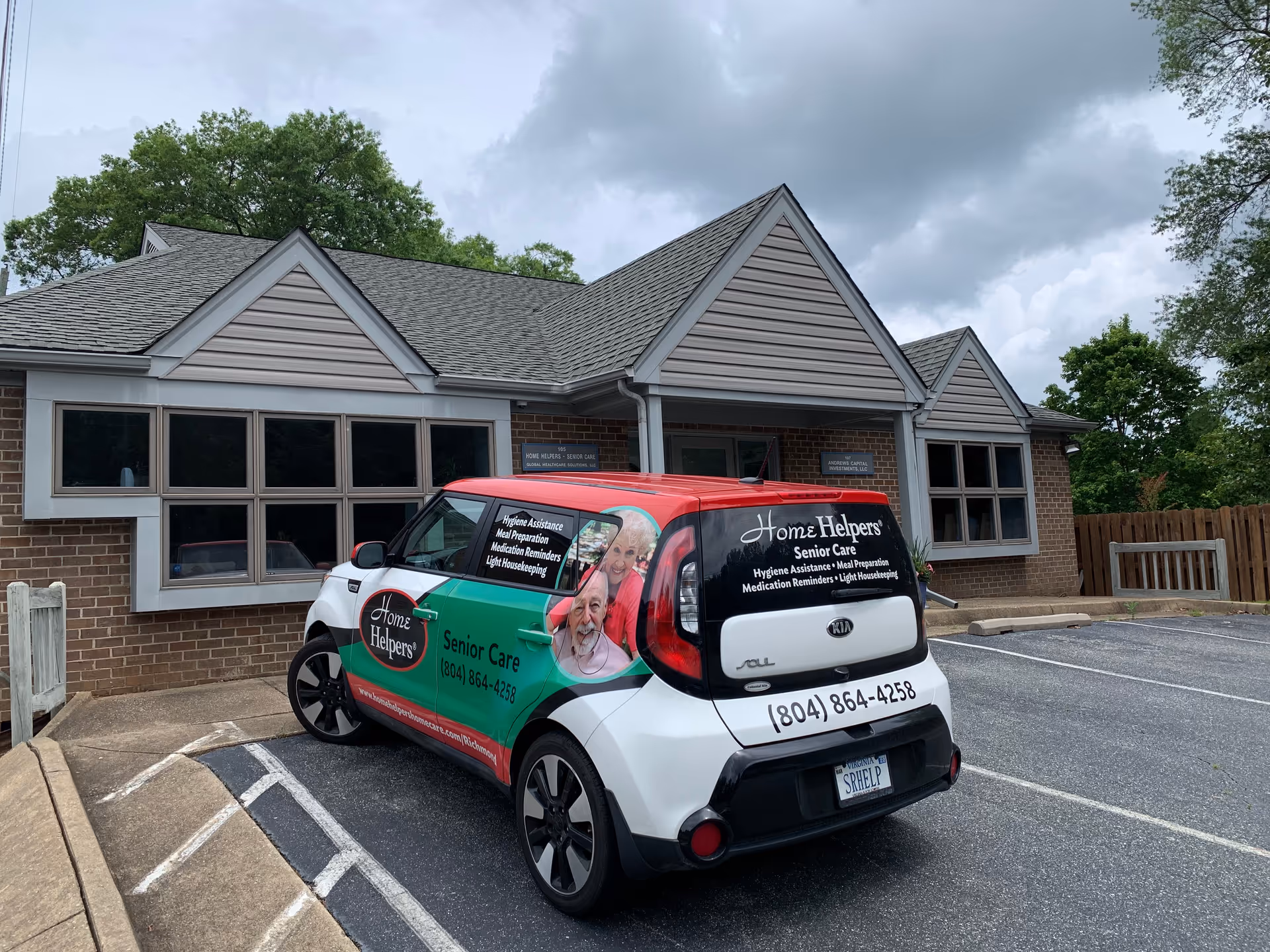 Brick senior care facility front with a colorful Home Helpers van parked outside.