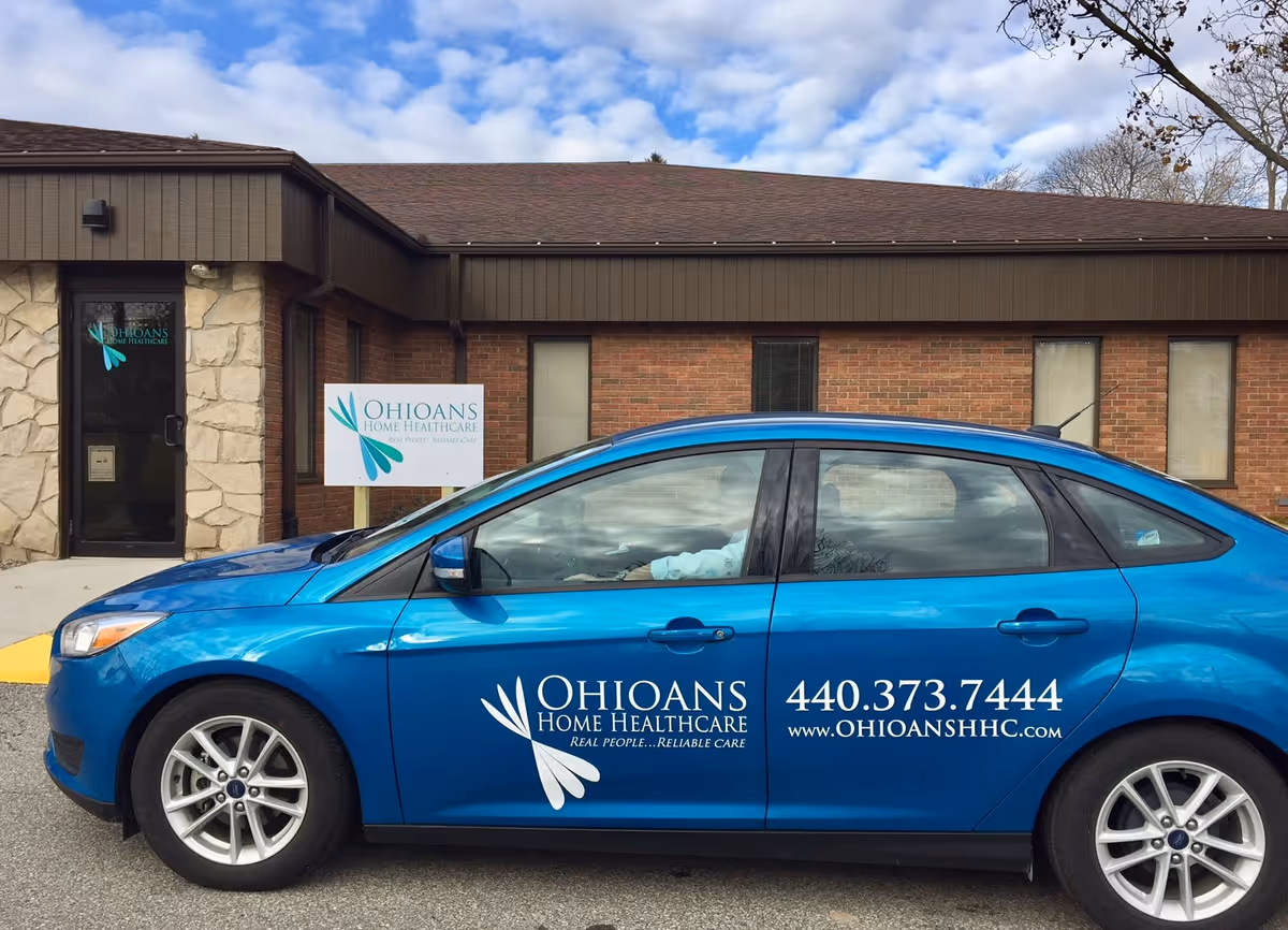 Blue car parked in front of a brick building with Ohioans Home Healthcare sign.