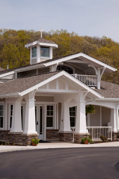 White senior living facility with a covered entrance and stone accents.