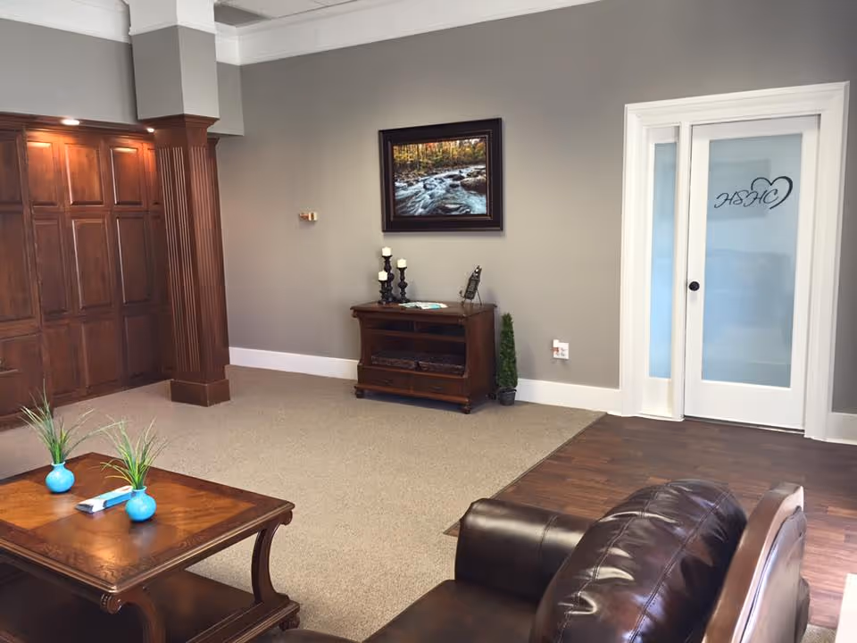 A cozy lobby area with brown leather sofa, coffee table, and wall art.