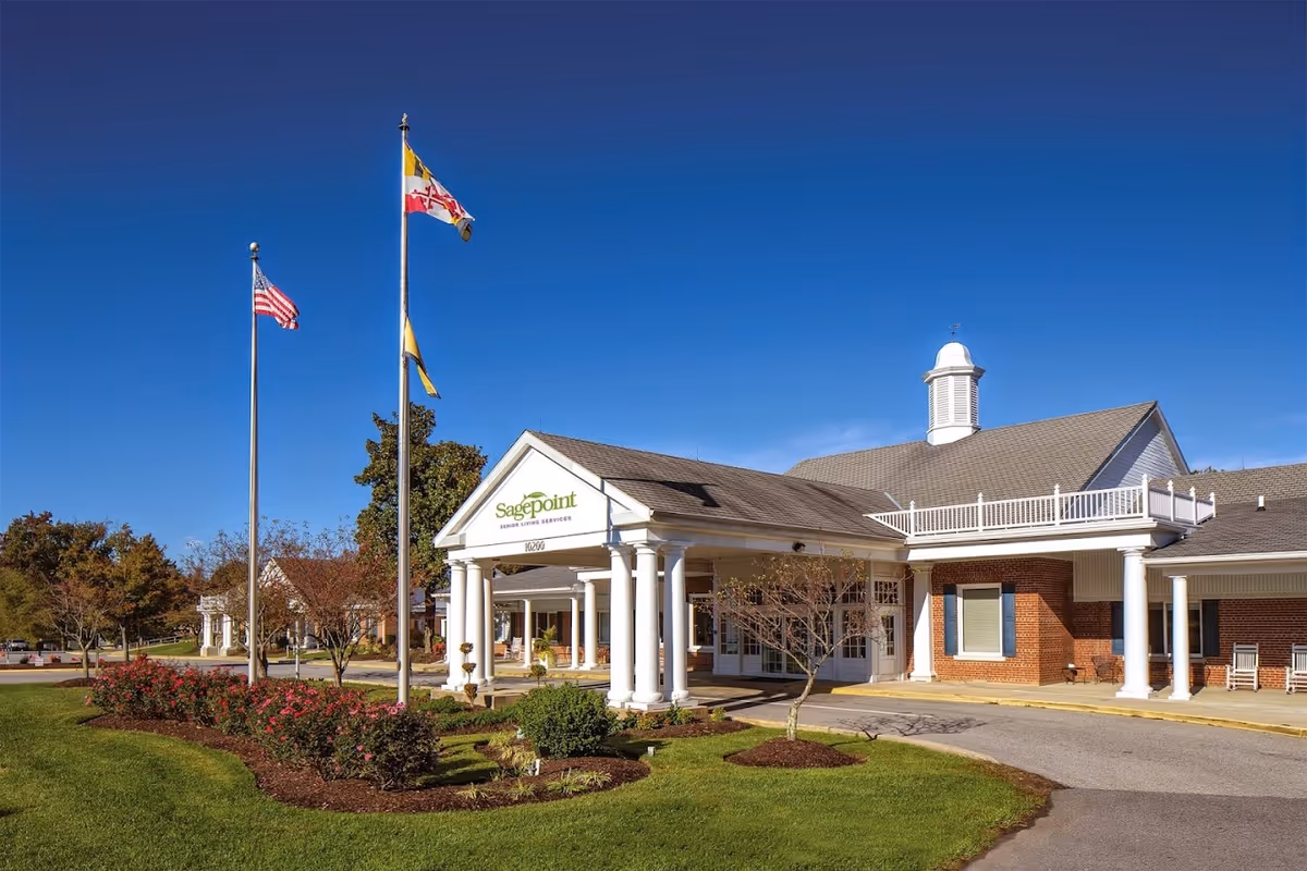 Exterior view of Sagepoint Senior Living Services building with flags and a covered entrance.