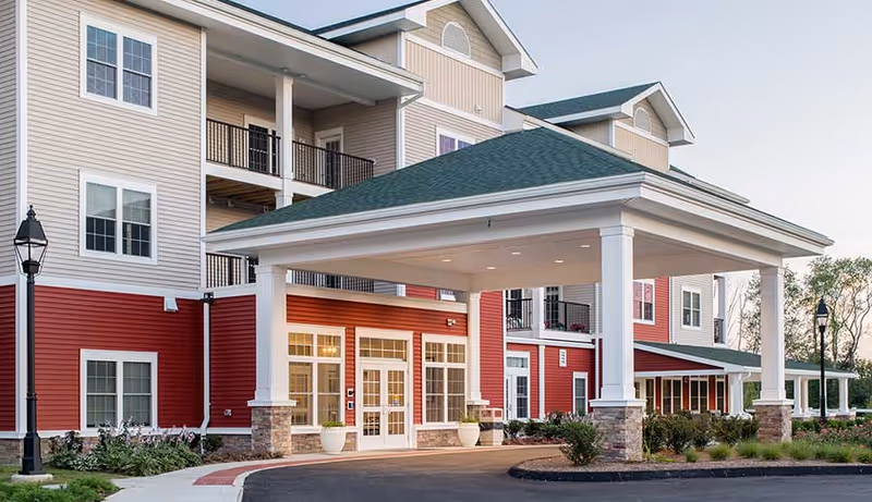 Exterior view of Colebrook Village at Hebron with a covered entrance and multiple buildings.