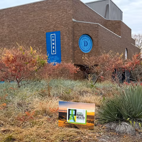 Brick facility building with blue signs and desert landscaping in foreground.