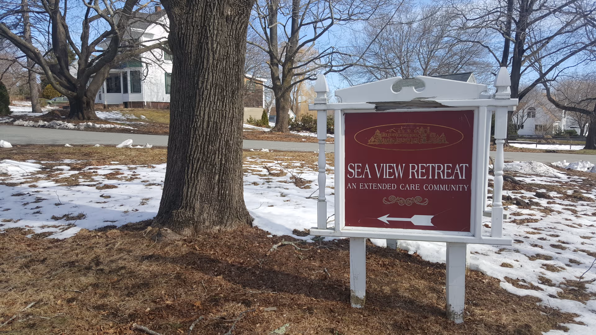 Outdoor sign for Sea View Retreat in a snowy, tree-lined residential area.