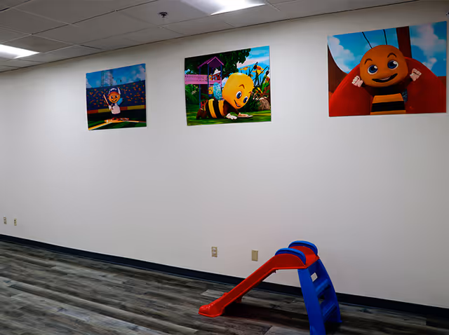 Interior play area with bee-themed wall art and a small red slide.