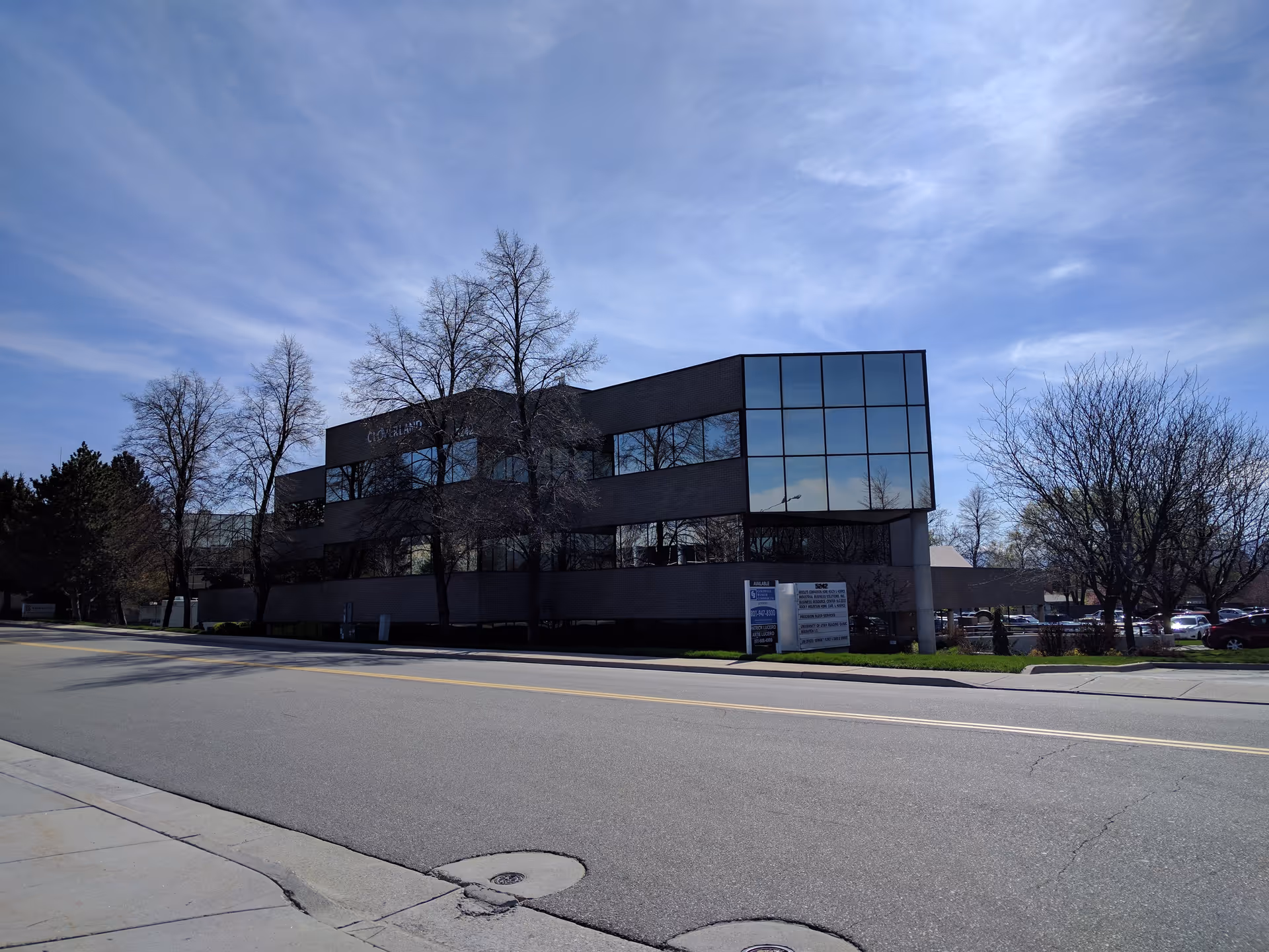 Exterior view of a modern office building with large glass windows and surrounding trees.