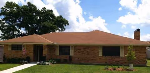 Single-story brick senior living facility with a brown roof and front lawn.