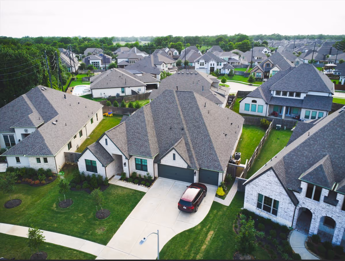 Aerial view of a suburban neighborhood with large houses and green lawns.