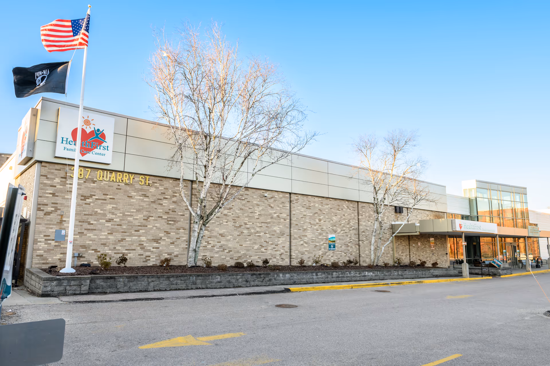 Exterior view of Health First Family Care Center building with flags and trees.