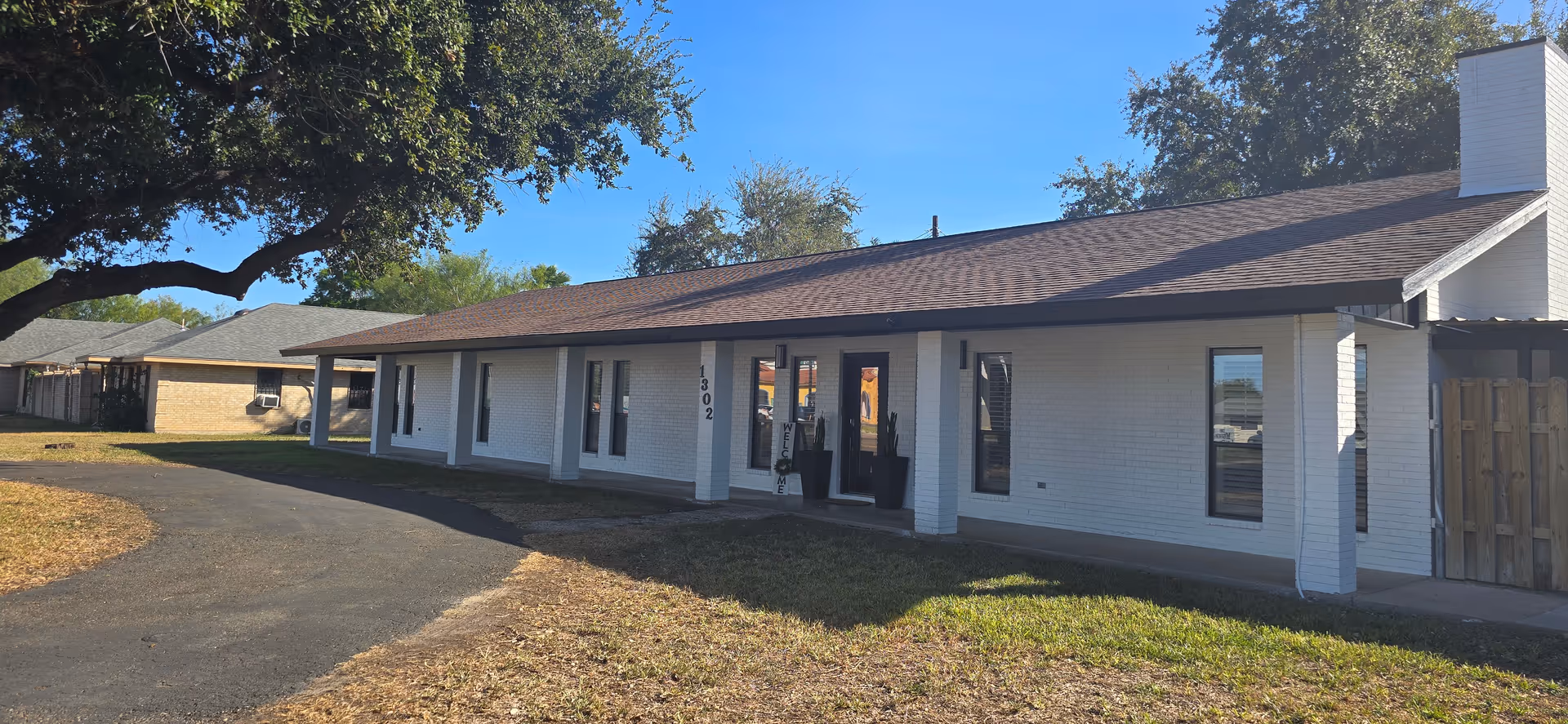 Single-story white brick senior care building with a covered front entrance.