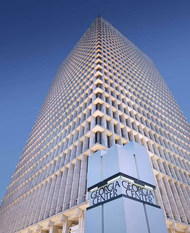 Tall glass-clad skyscraper photographed from base with Georgia Center sign at entrance.