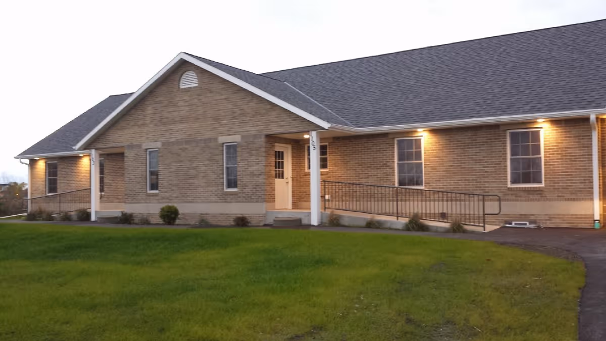 Brick exterior of a senior living facility with a ramped entrance and lights.