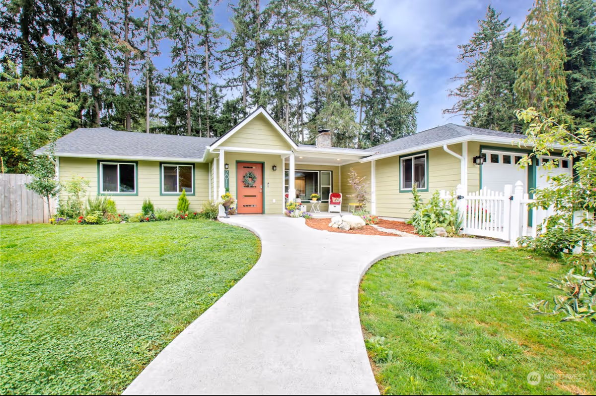 Front exterior view of a single-story green senior living home with curved walkway.