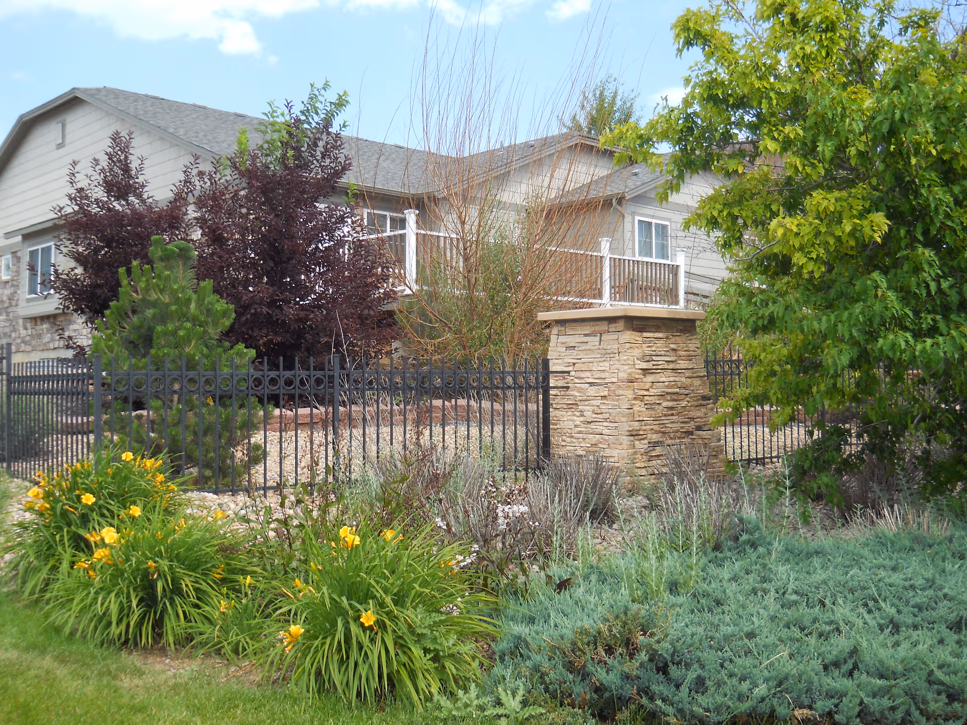 Exterior view of Phoenix Senior Living with a landscaped garden and stone pillar.