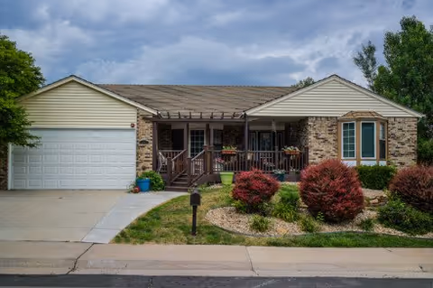 Single-story brick home with a front porch, driveway, and landscaped yard.