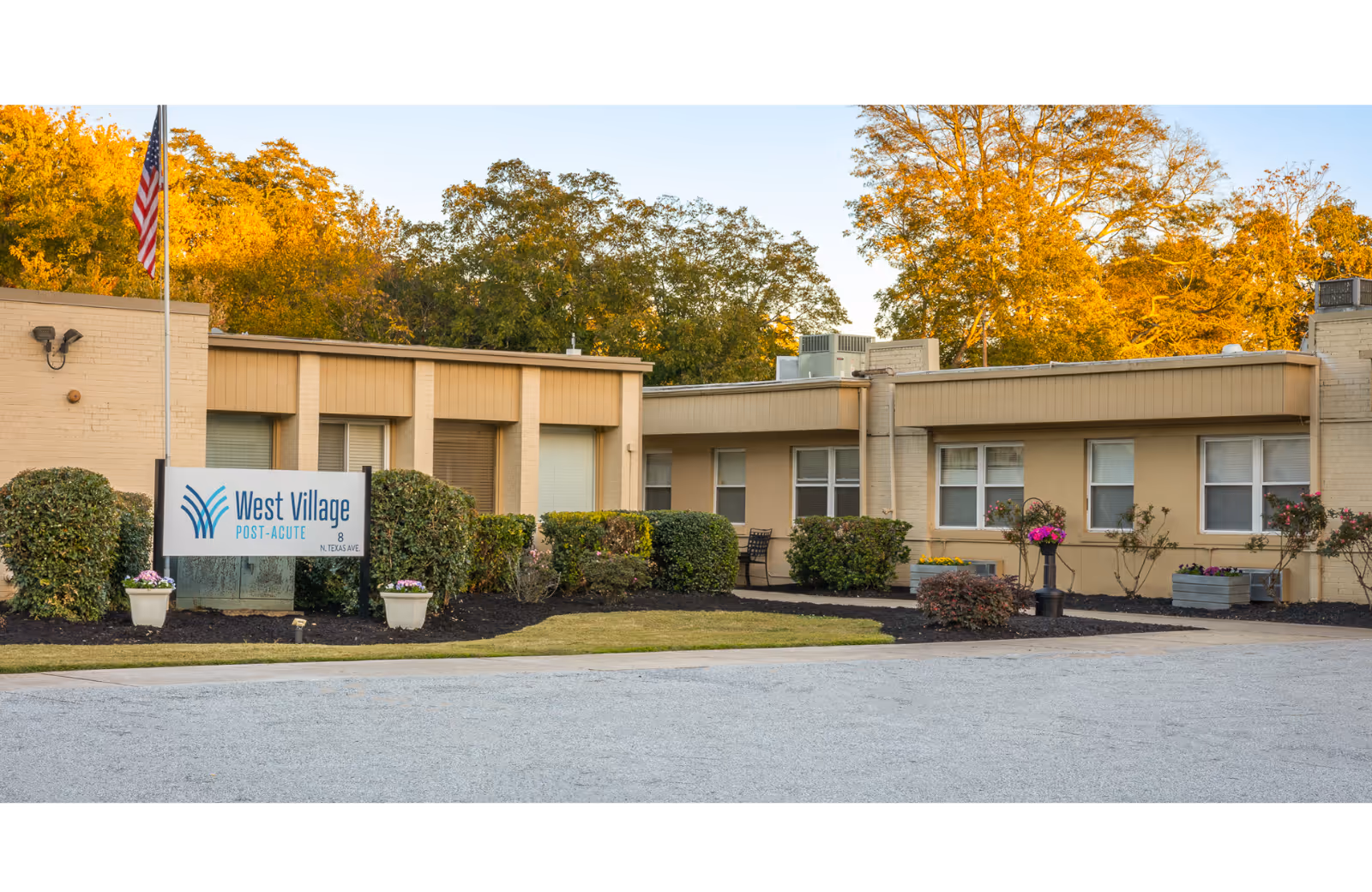 Single story beige senior care building with a West Village Post-Acute sign and landscaping.