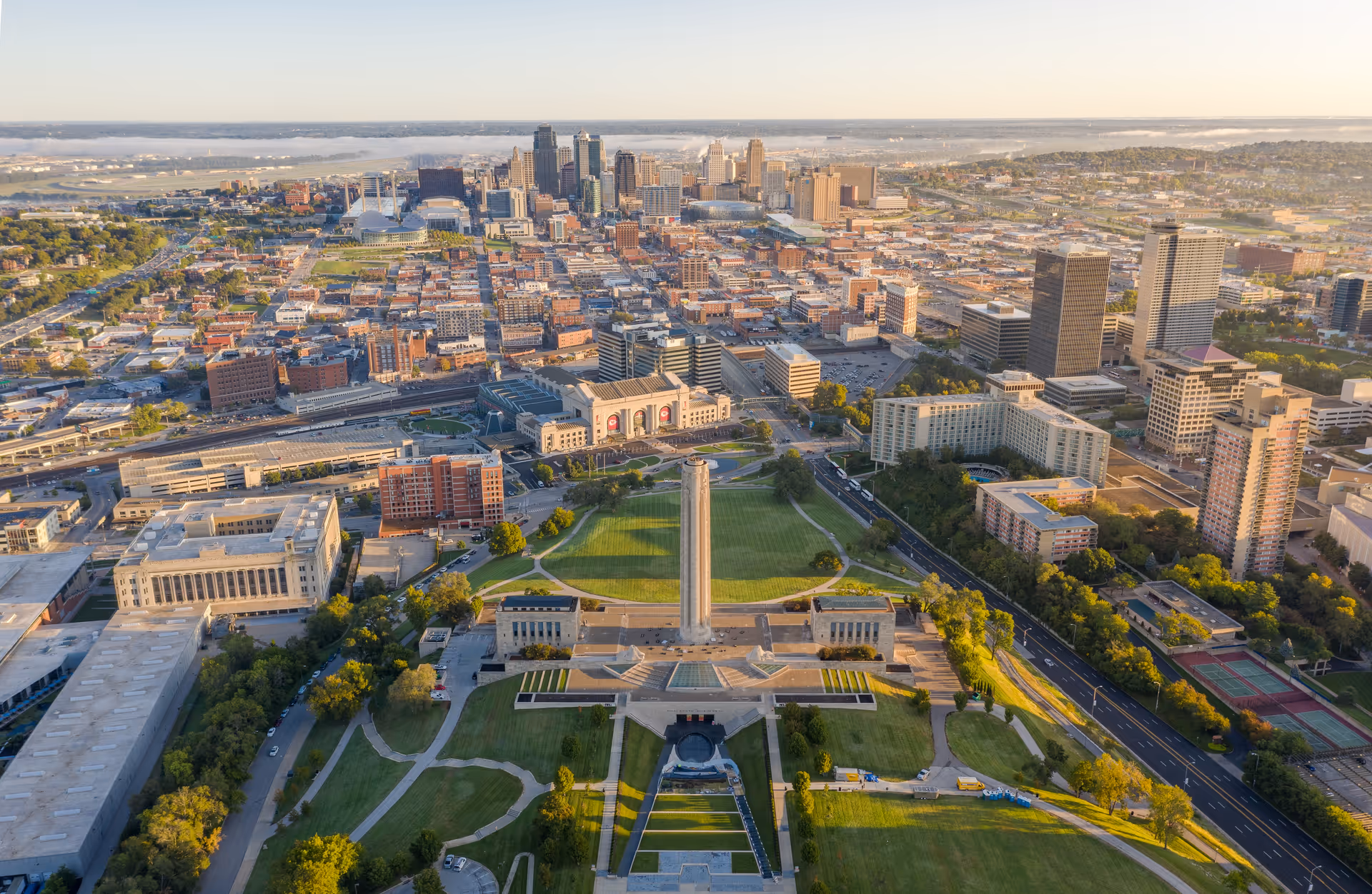 Aerial cityscape featuring a central obelisk tower and expansive green park.