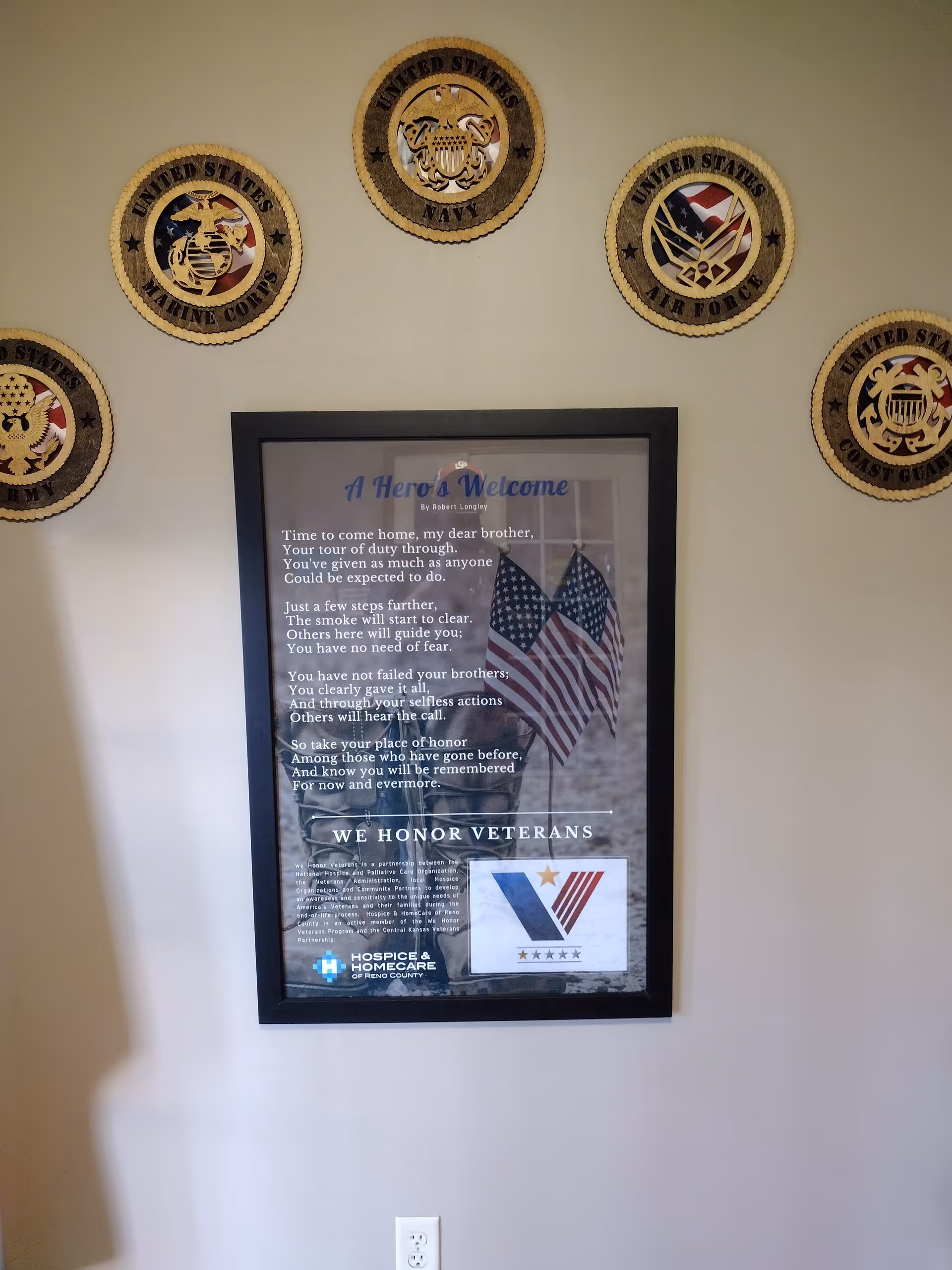 Interior wall with veteran emblems and a framed welcome poster
