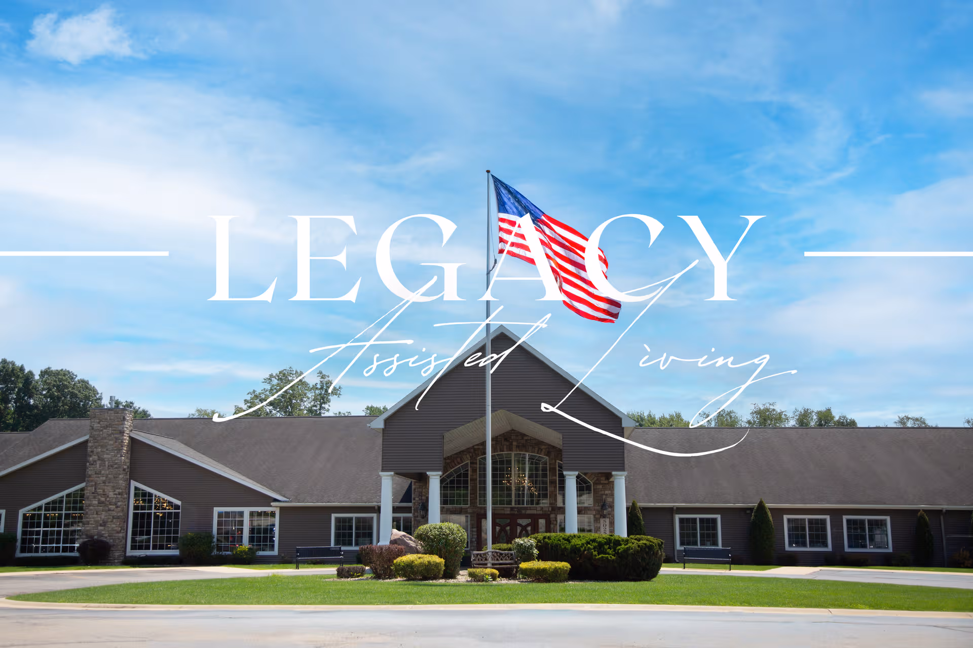 Exterior view of a single-story assisted living facility with a flag and manicured landscaping.