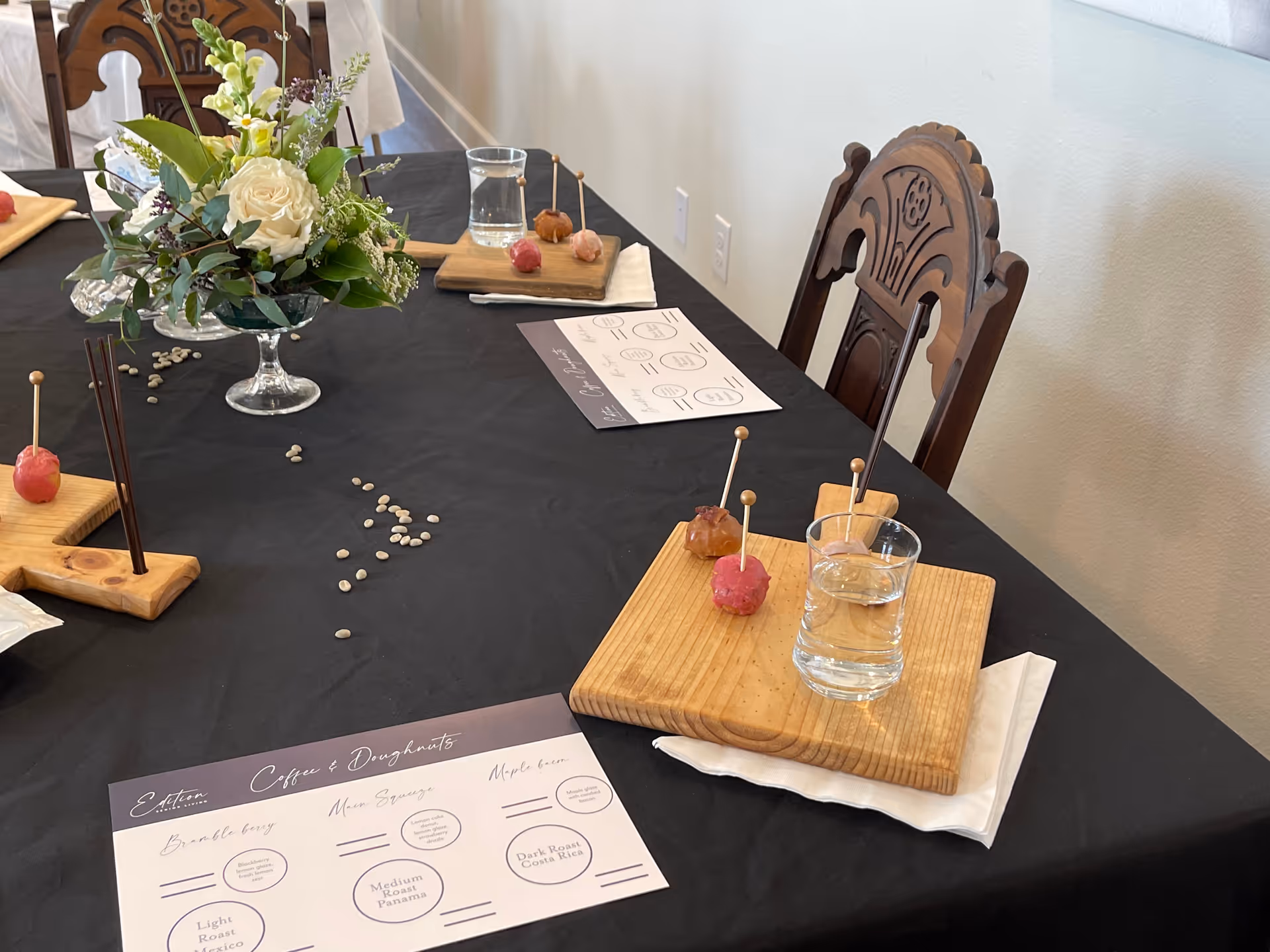 Table set for a meal with floral centerpiece, skewers, and menus.