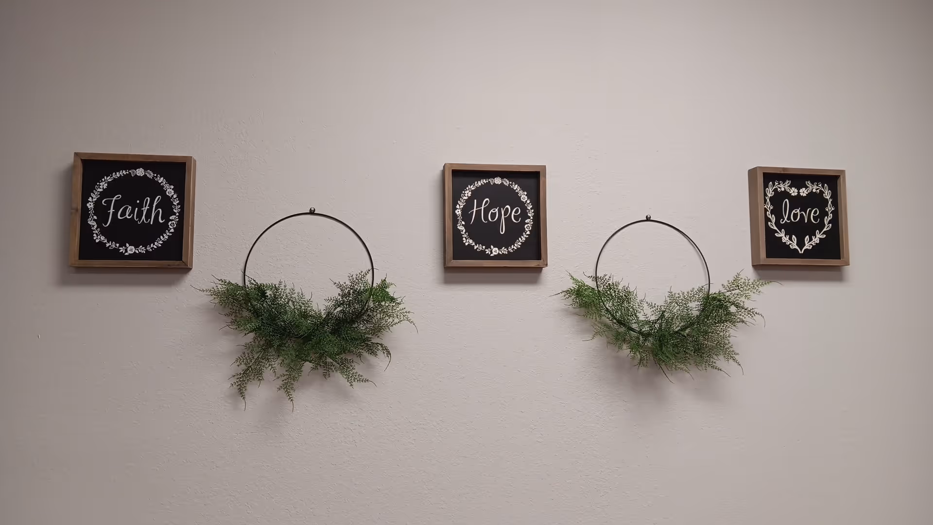 Interior wall adorned with Faith, Hope, Love framed art and greenery.