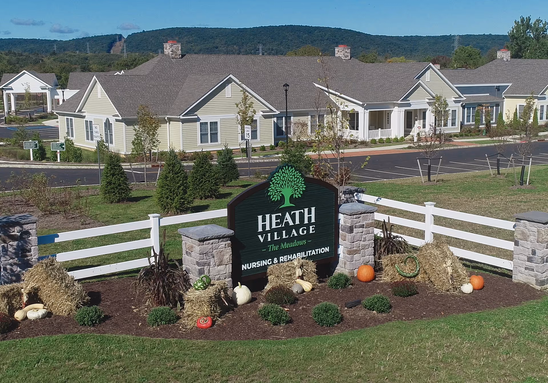 Exterior view of Heath Village Meadows facility with landscaped entrance sign and buildings.