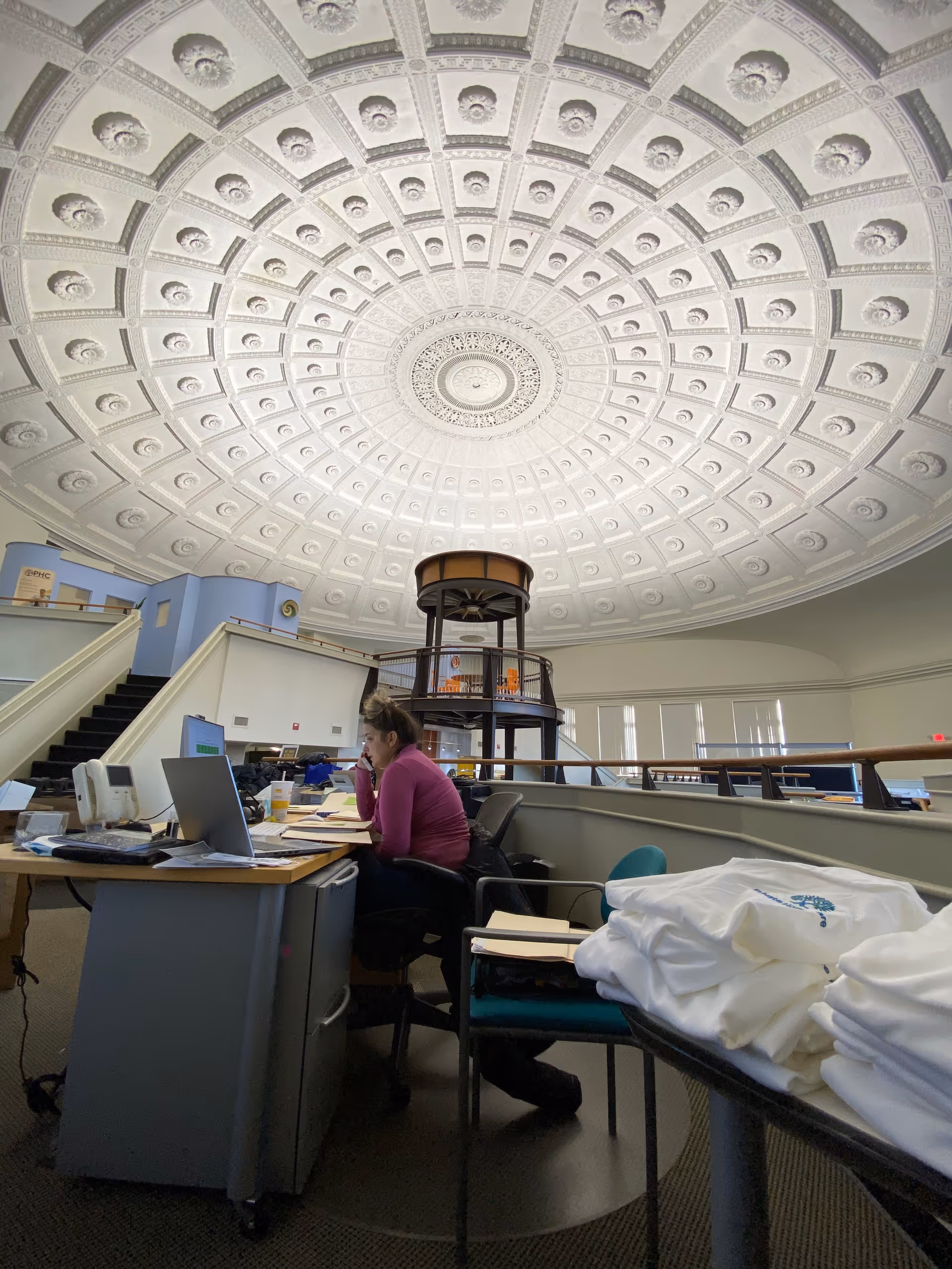Administrative desk area under a large ornate circular ceiling, with a staff member working.