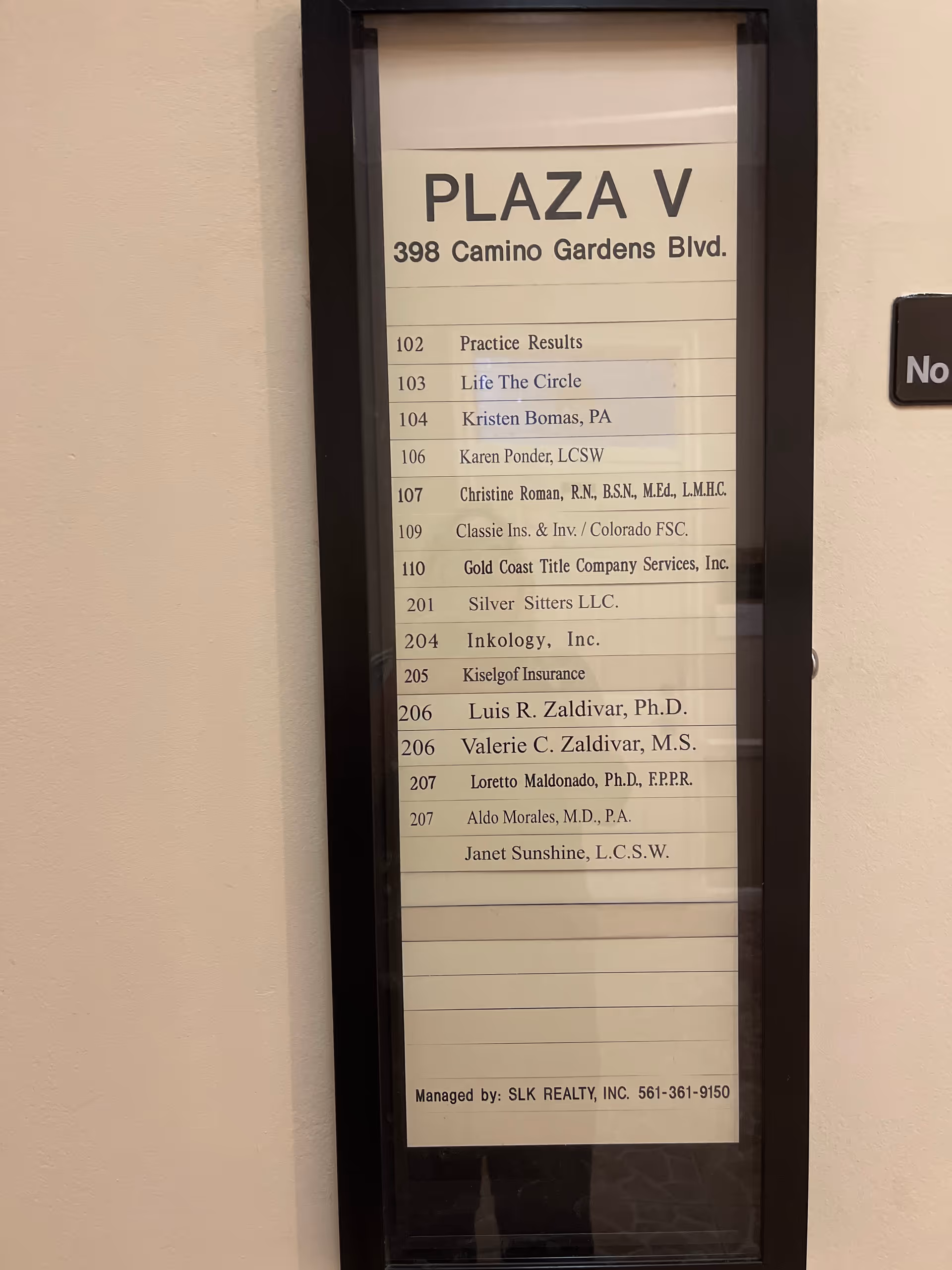 Tall glass-framed directory sign listing tenants and suite numbers in a hallway.