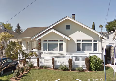 White, single-story senior living facility with a front porch and manicured lawn.