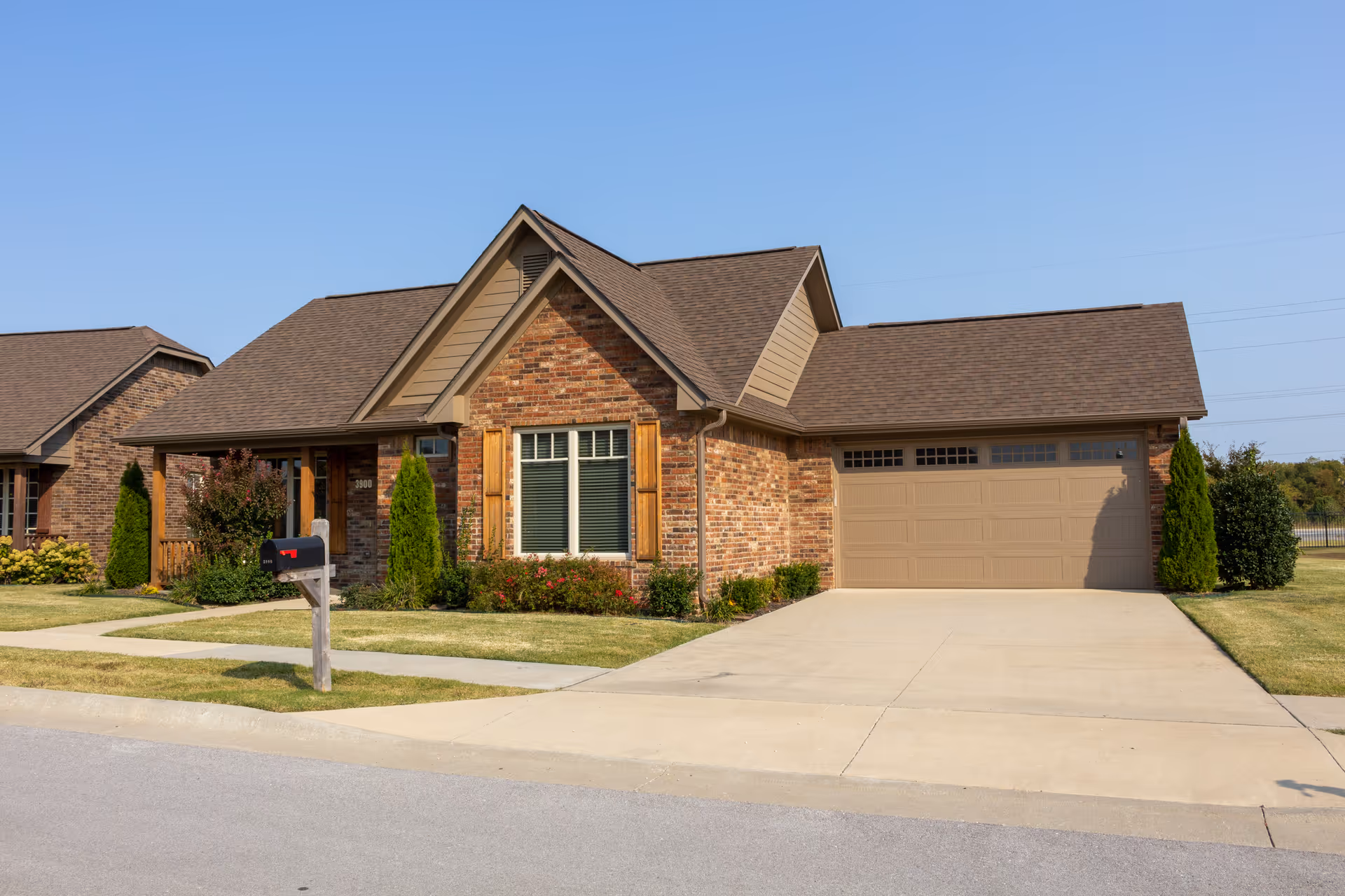 A brick suburban home with a two-car garage and manicured lawn.